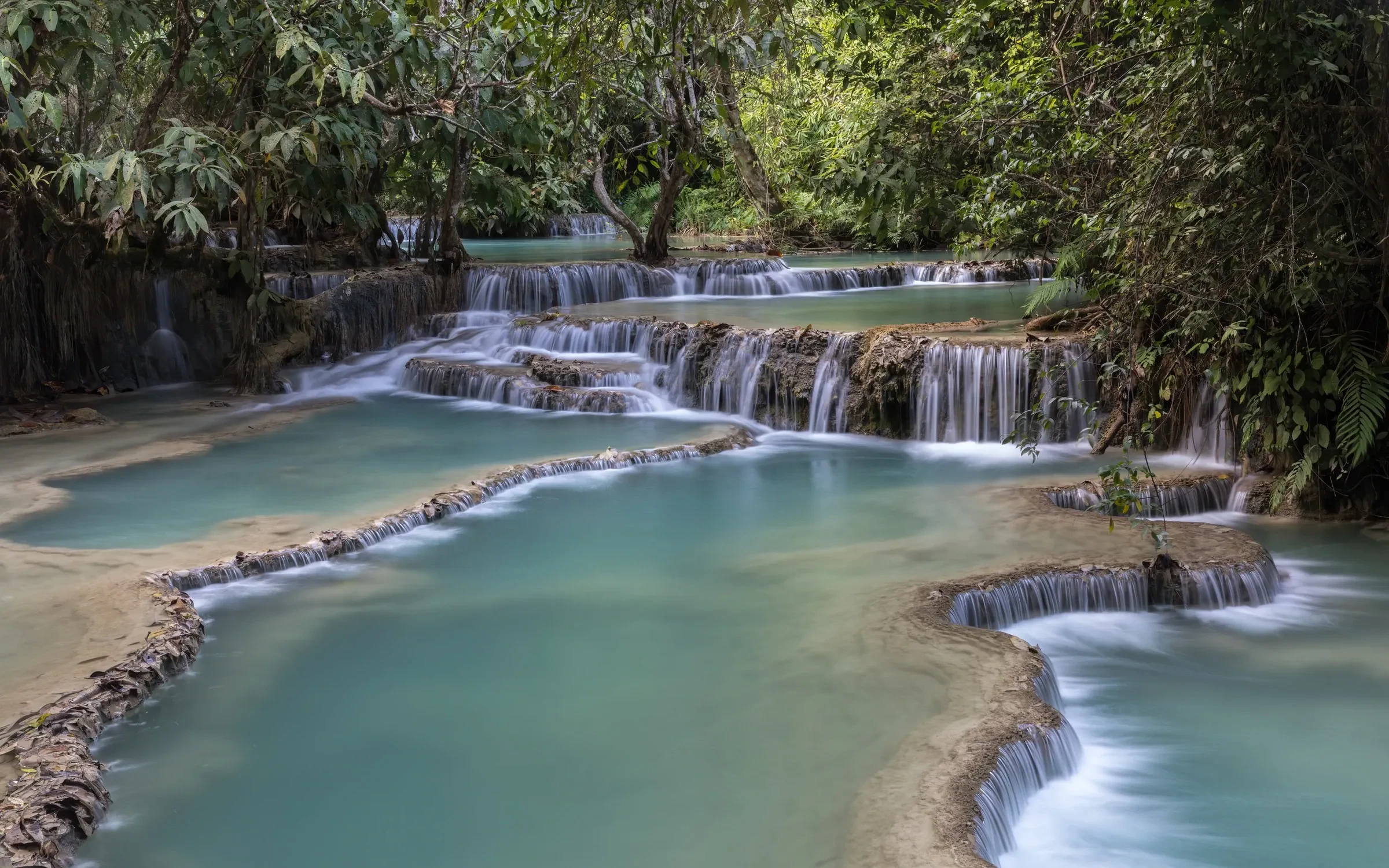 The turquoise tiered pools of Kuang Si Falls in the forest near Luang Prabang