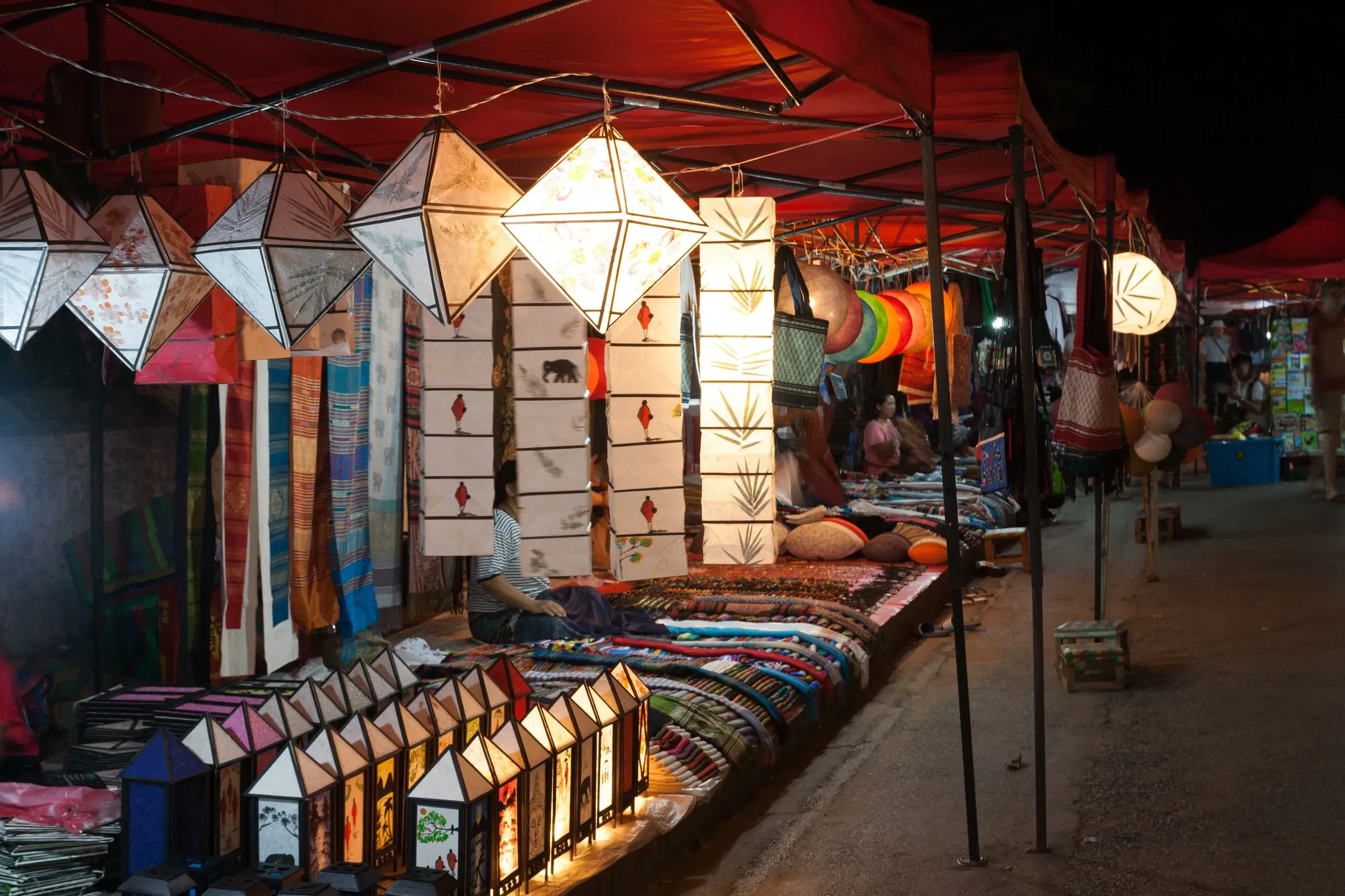 Paper lanterns and textiles for sale at a stall in the Luang Prabang night market