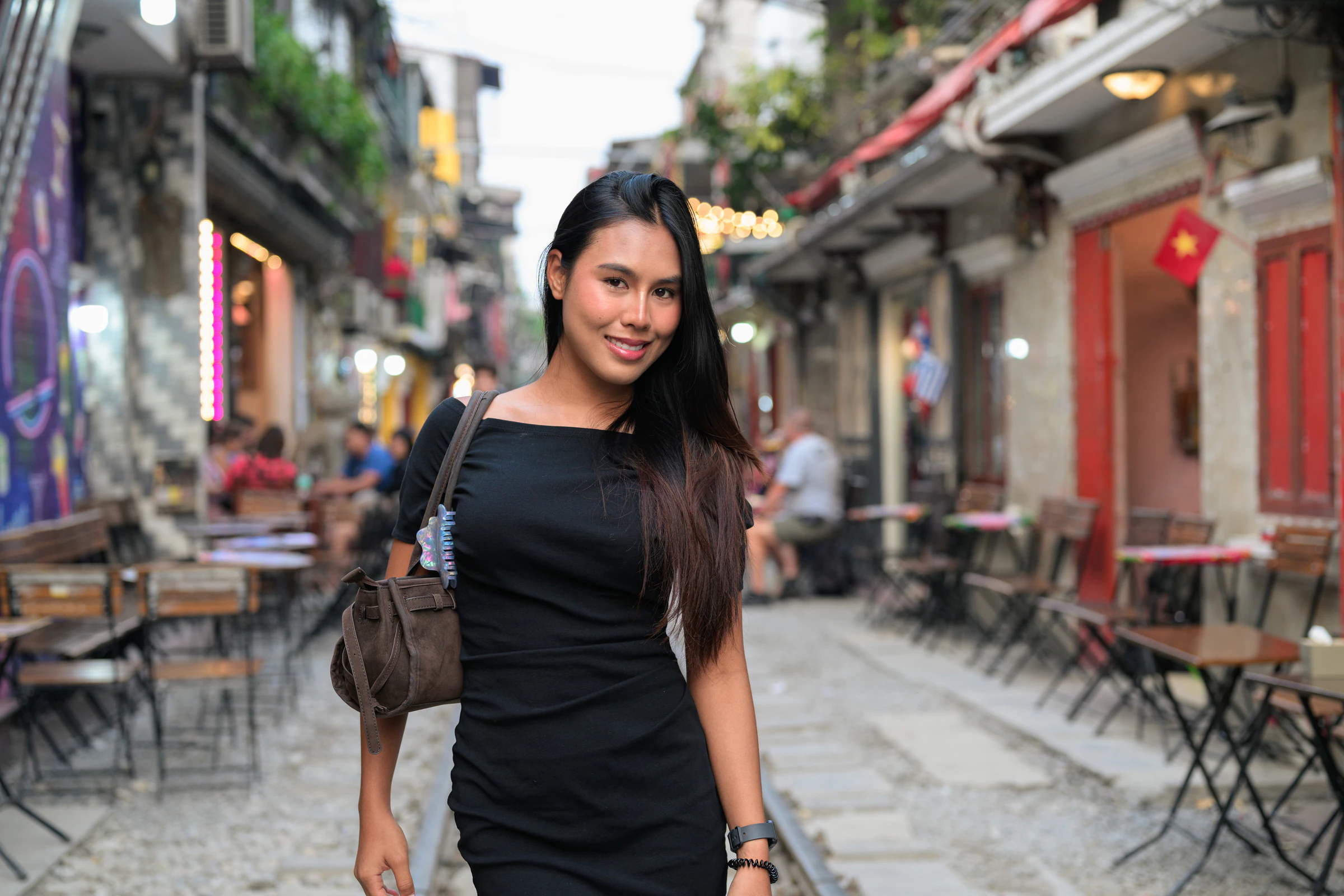 A narrow cafe-lined street in central Hanoi with a woman standing in the foreground