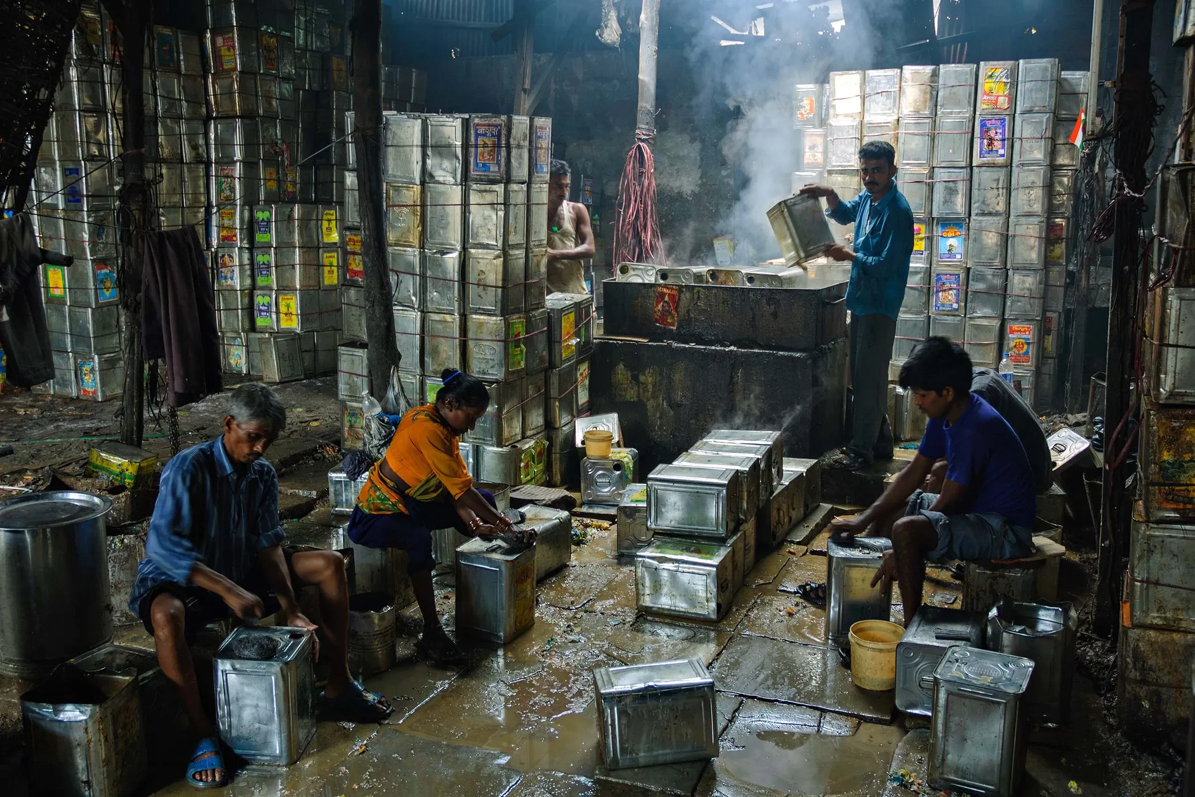 Workers cleaning metal drums for reuse in a Dharavi workshop