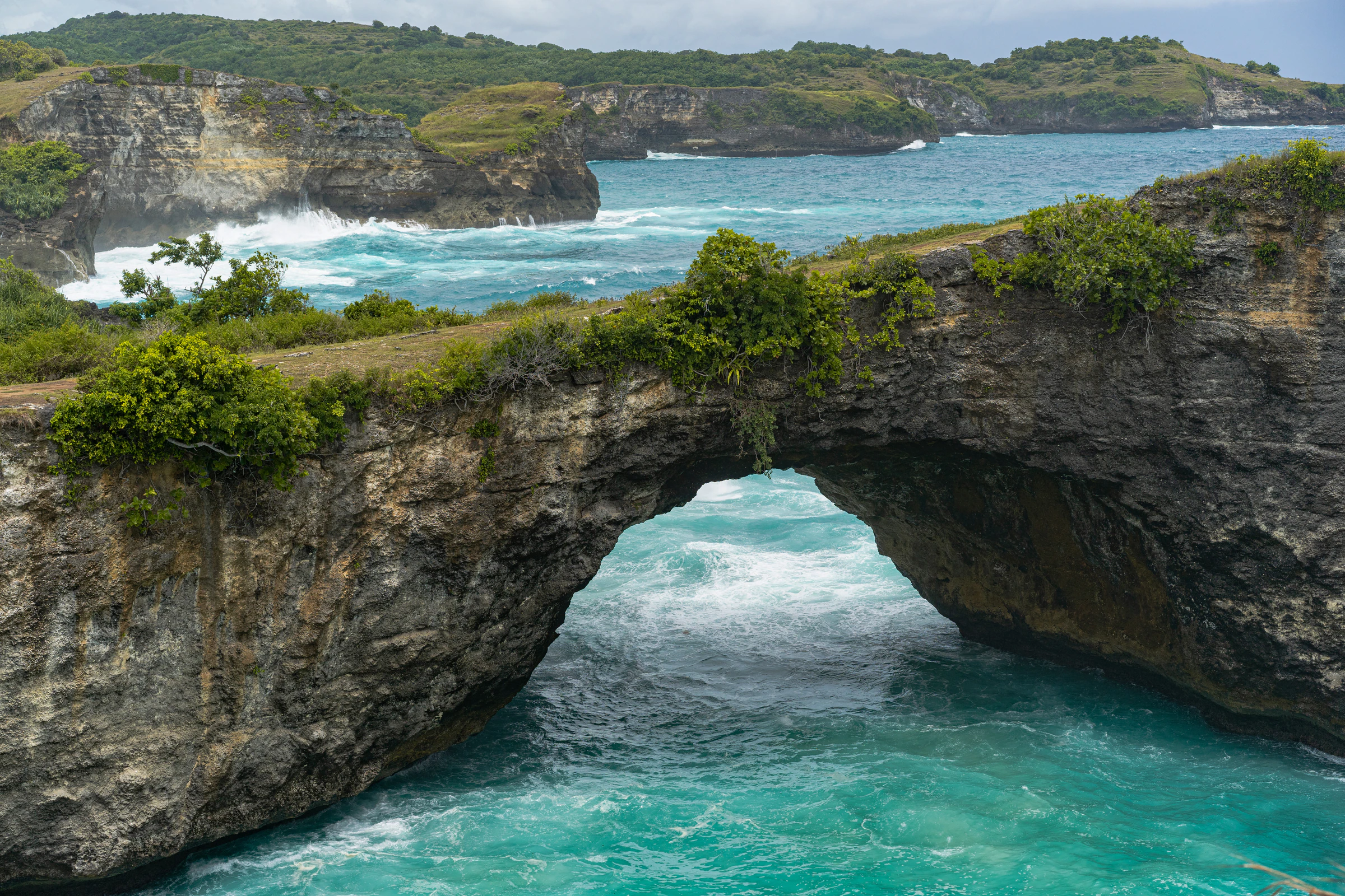 A natural rock arch over turquoise water on Nusa Penida's west coast