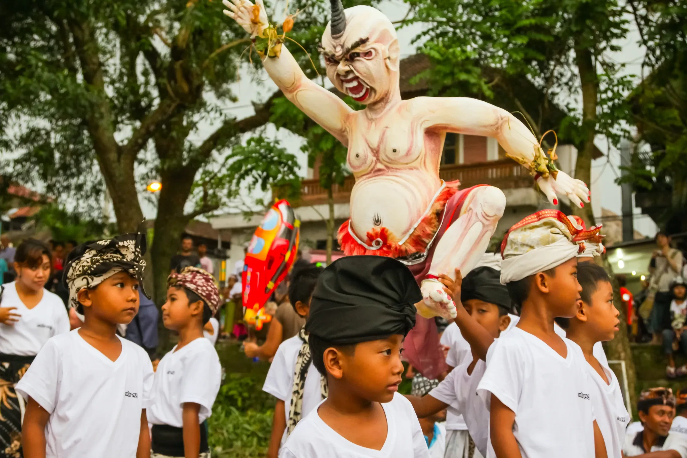 Ogoh-ogoh figures among a crowd of villagers in white at a Ngrupuk parade in Ubud, Bali