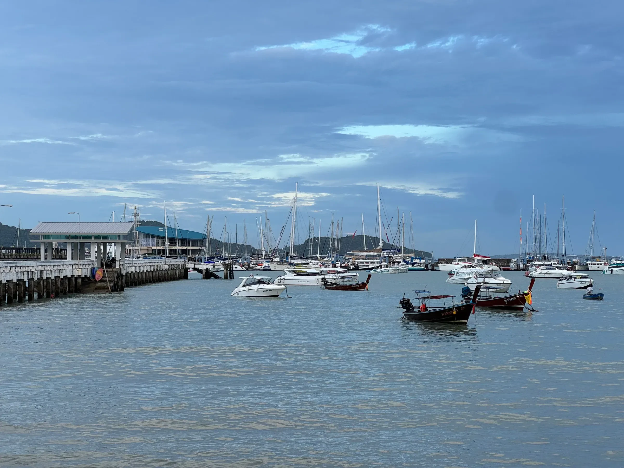 A ferry pier on Phuket with longtail boats and a speedboat waiting alongside