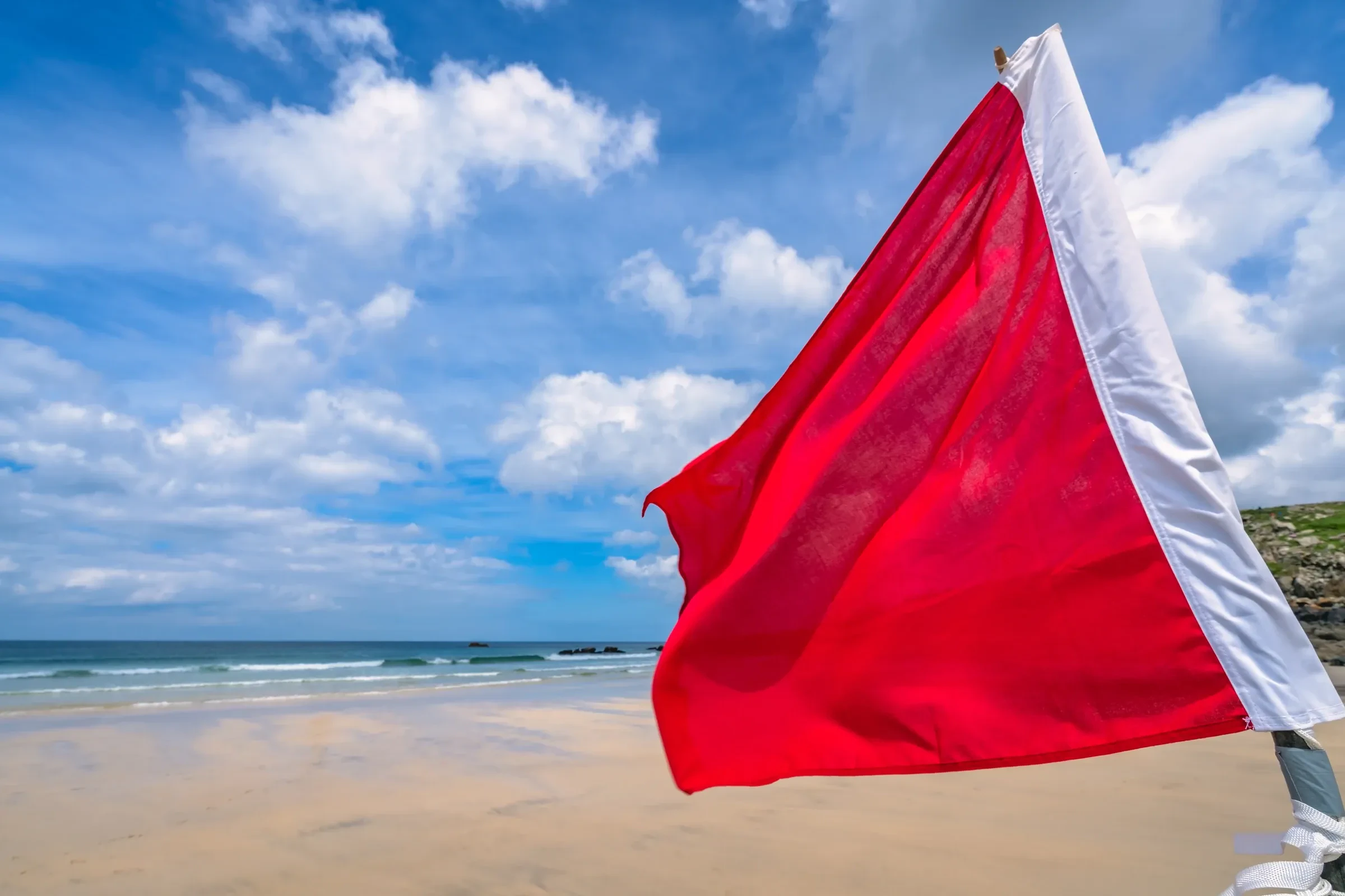 A red warning flag planted in the sand on a west-coast Phuket beach