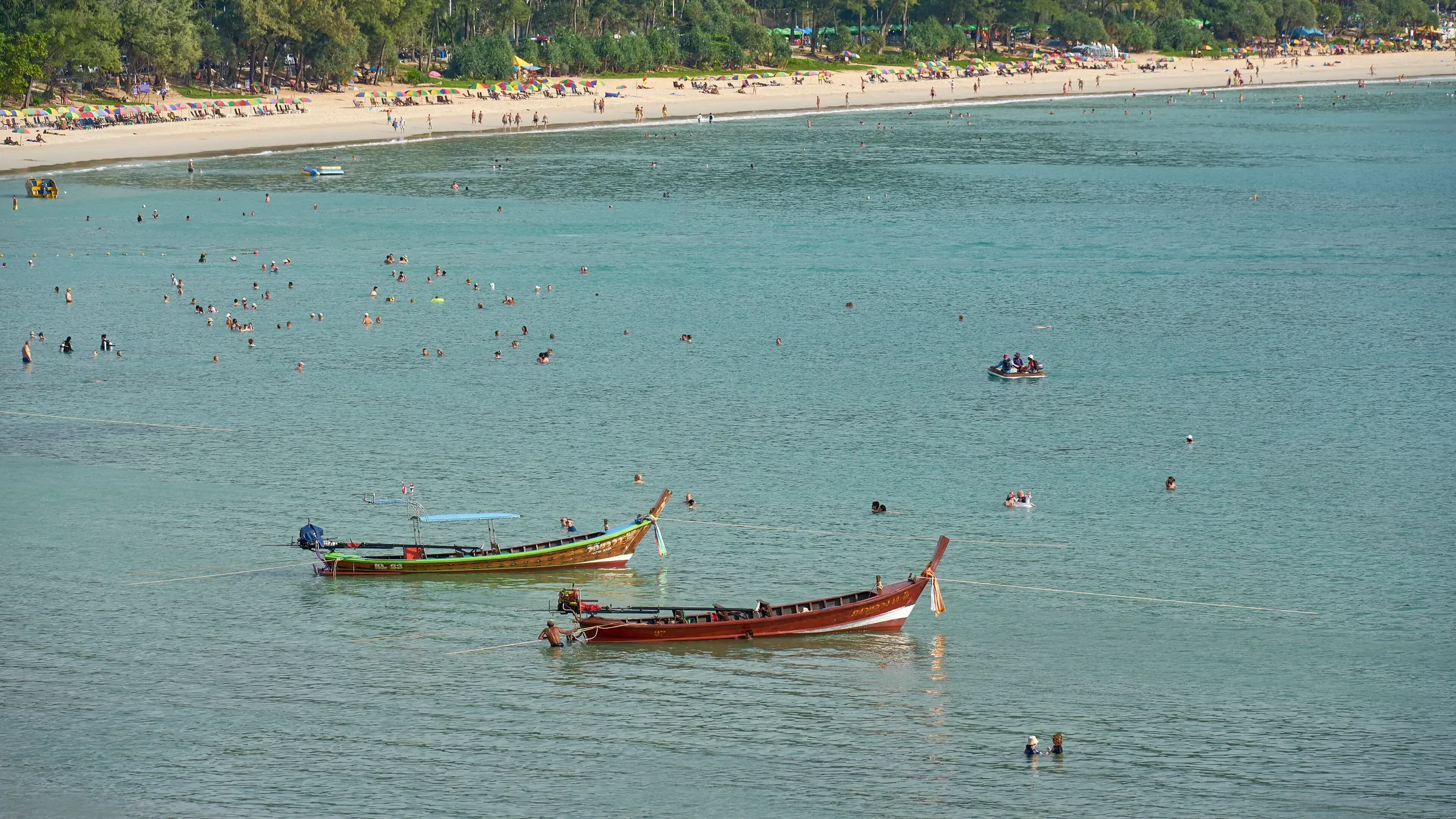 Longtail boats on calm, clear water off Kata Beach in Phuket's dry season