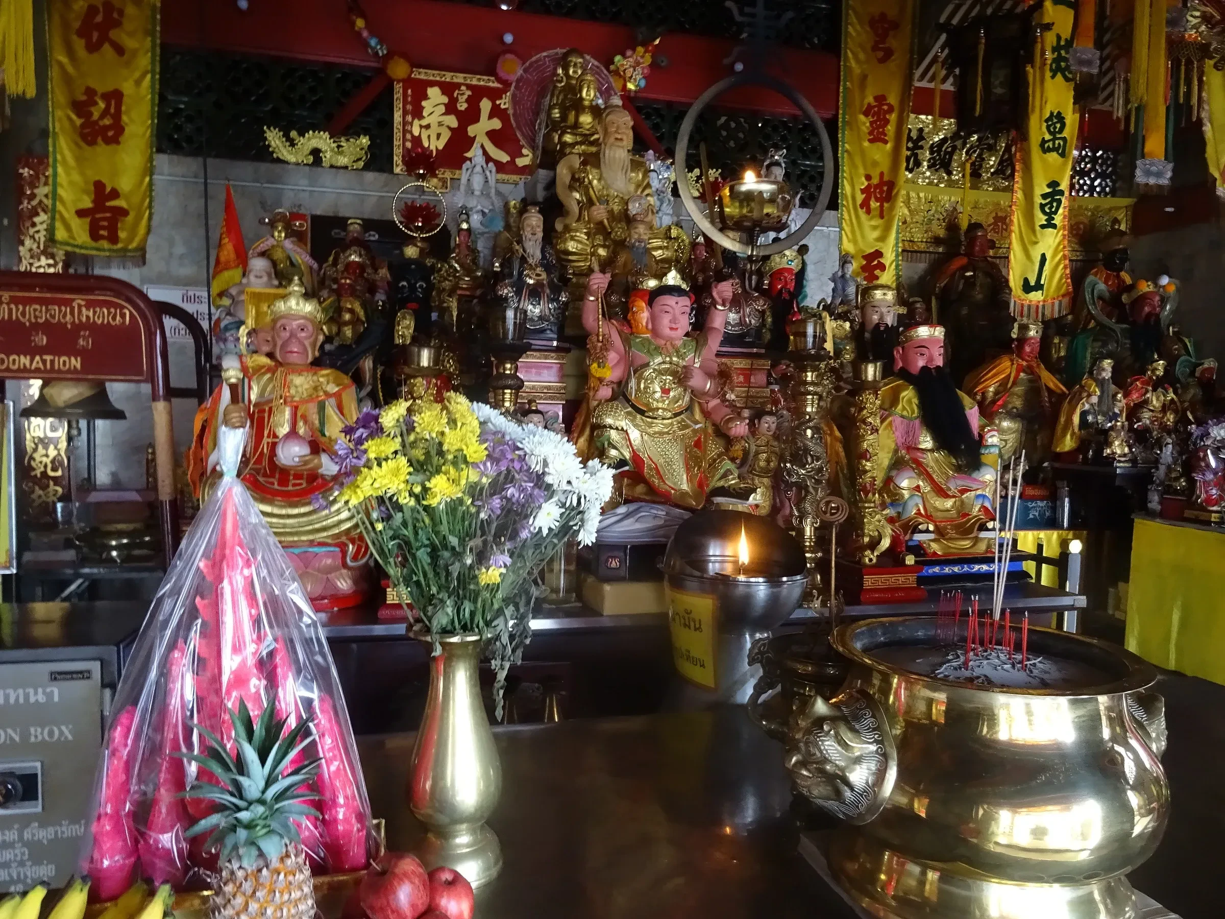 An altar inside Jui Tui Shrine with deity statues, flowers, fruit offerings and yellow banners