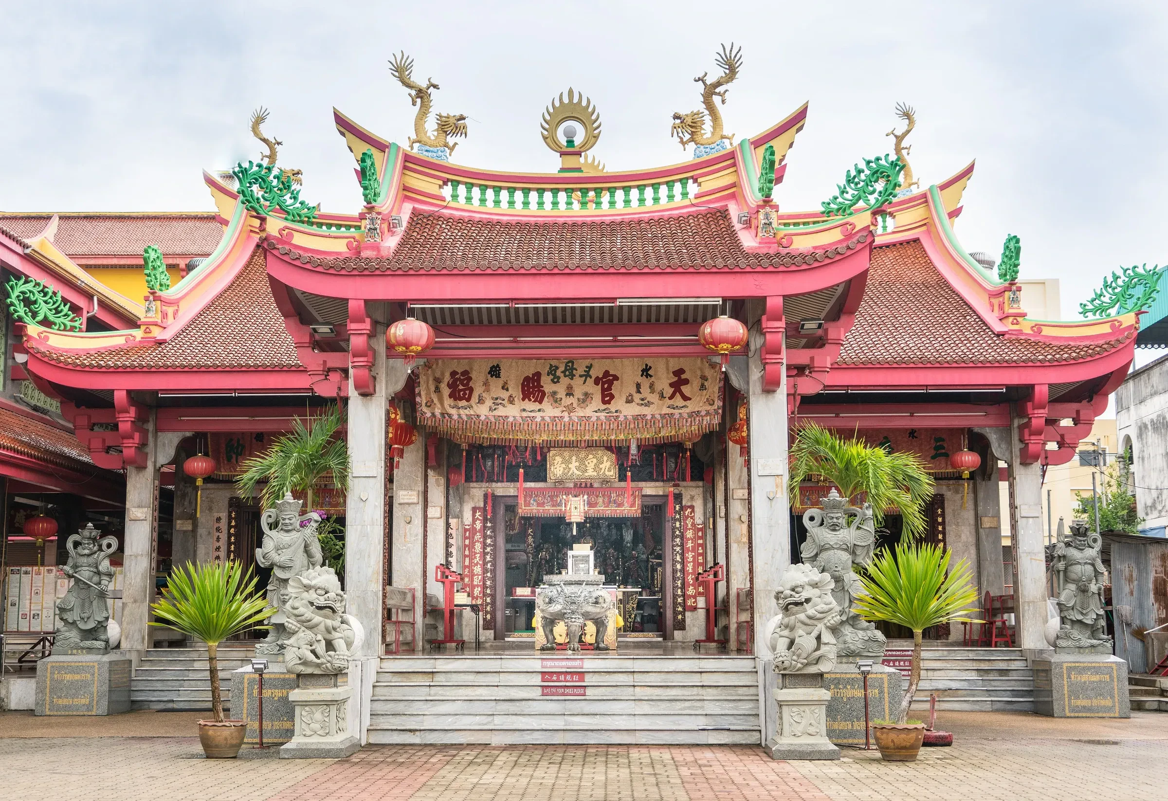 The red and gold front of Jui Tui Shrine in Phuket Town, with stone lions and hanging lanterns