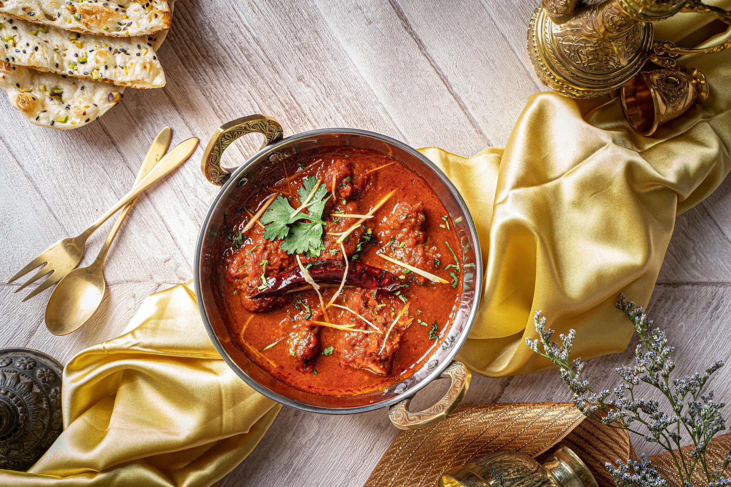 A kadai of laal maas, the fiery red Rajasthani mutton curry, served with flatbreads