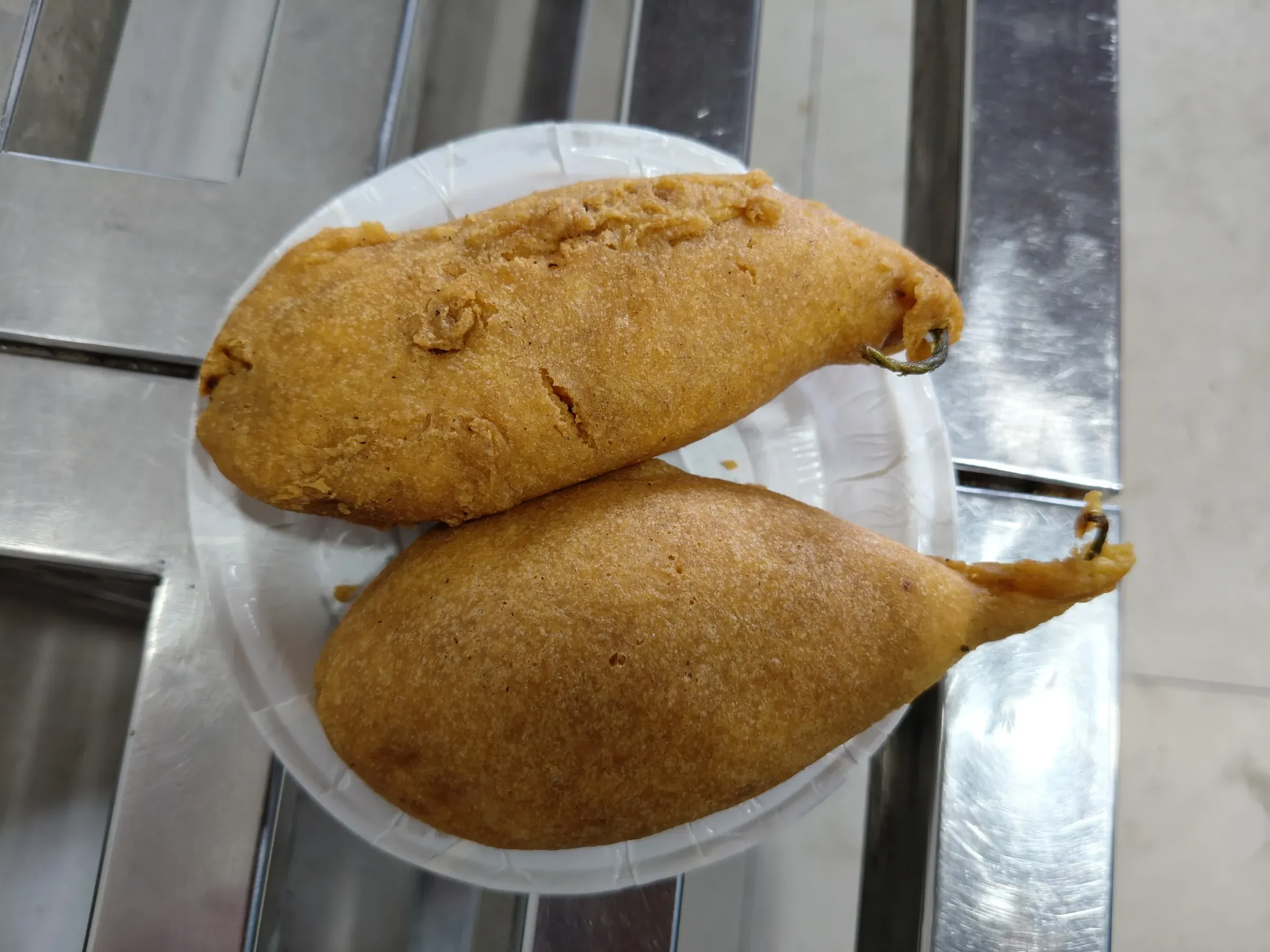 Two mirchi vada, whole green chillies fried in gram flour batter, on a plate in Jodhpur