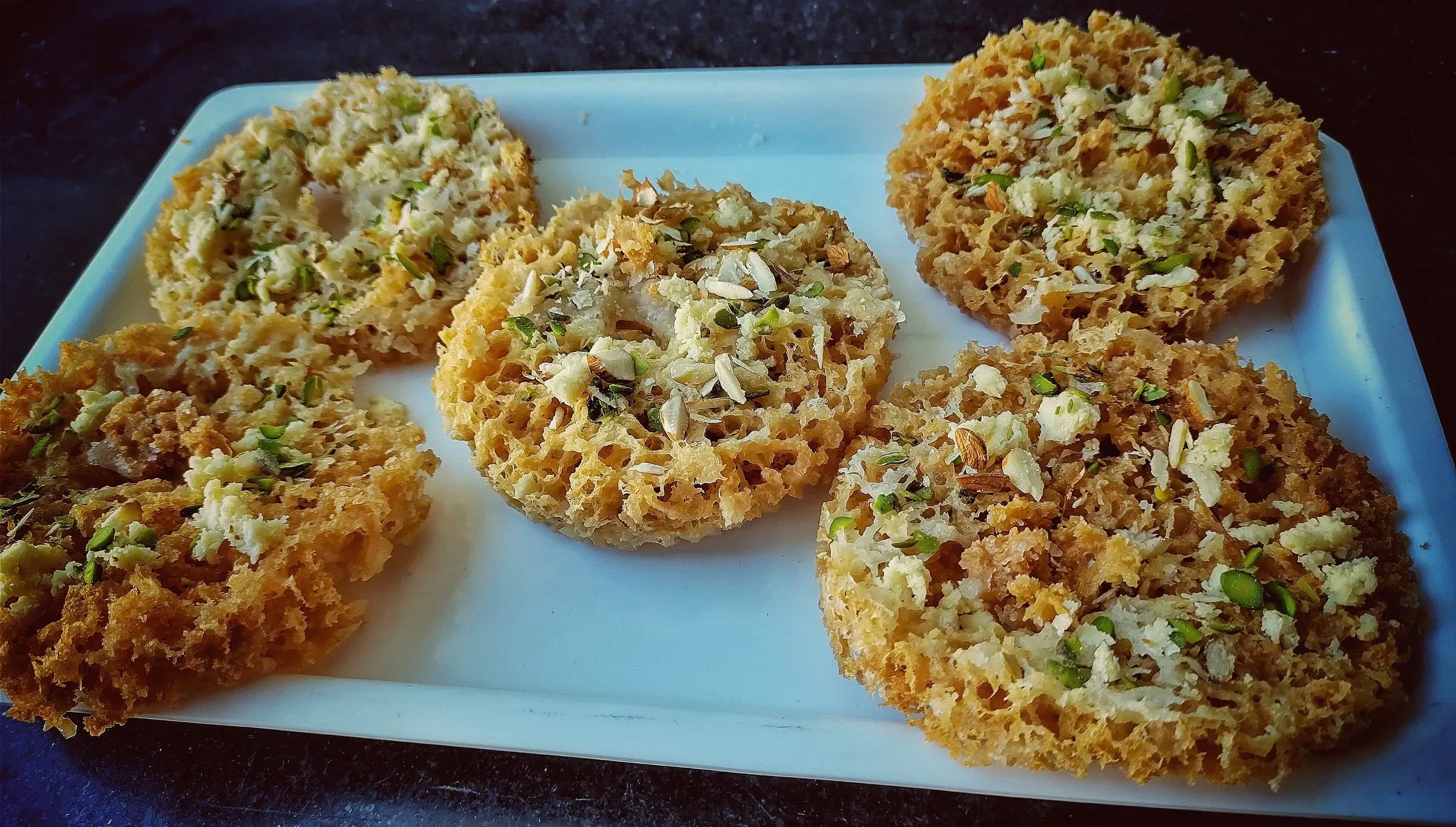 Ghewar, the honeycombed Rajasthani sweet, topped with chopped nuts
