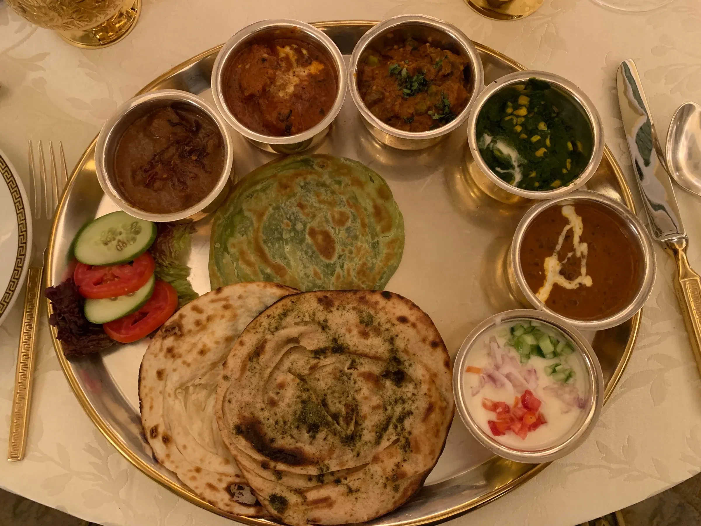 A Rajasthani thali with small bowls of curry, flatbreads and salad on a metal plate at a hotel restaurant in Jaipur