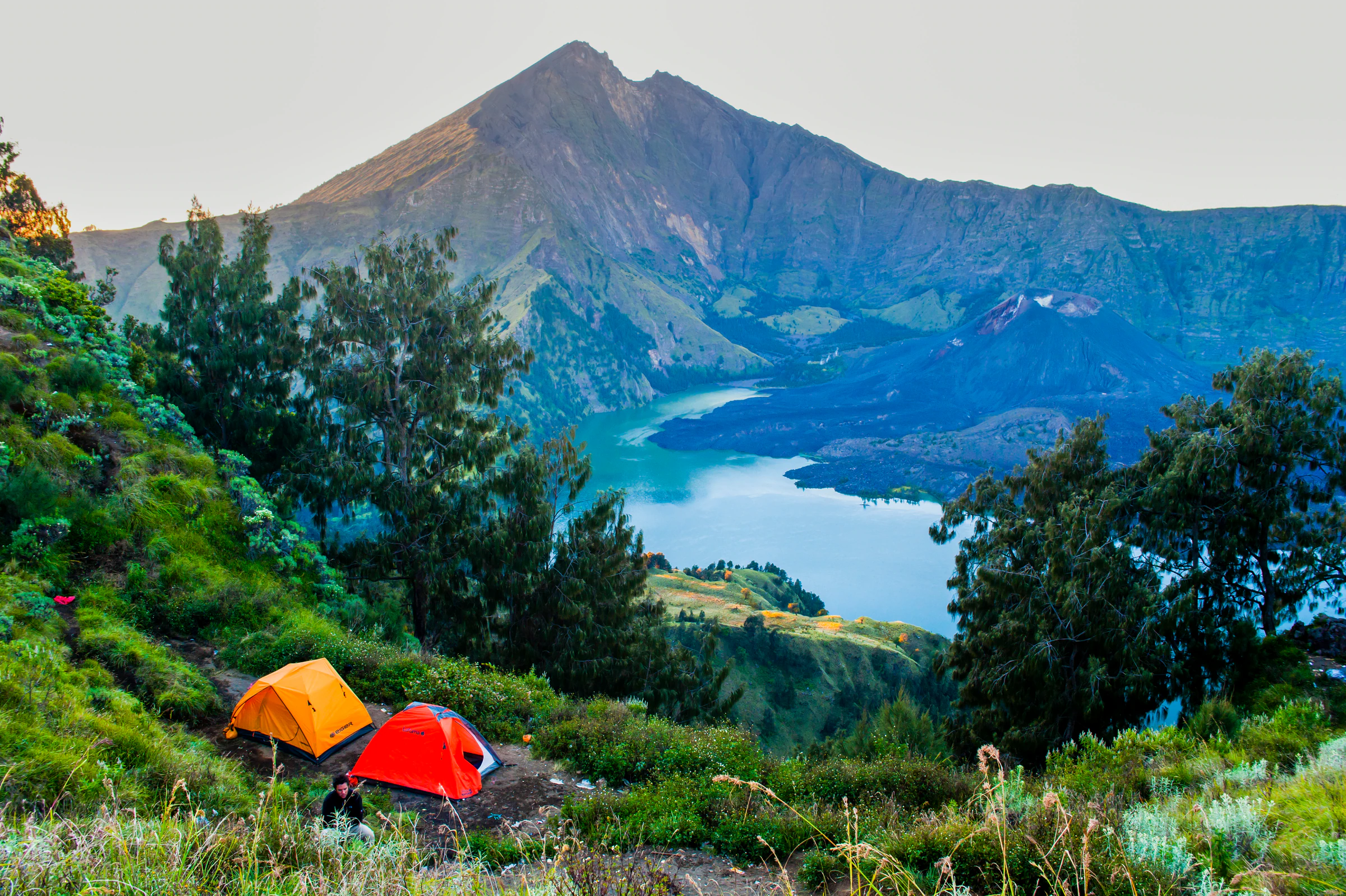 Two tents pitched on the crater rim of Mount Rinjani, with the lake and the summit behind