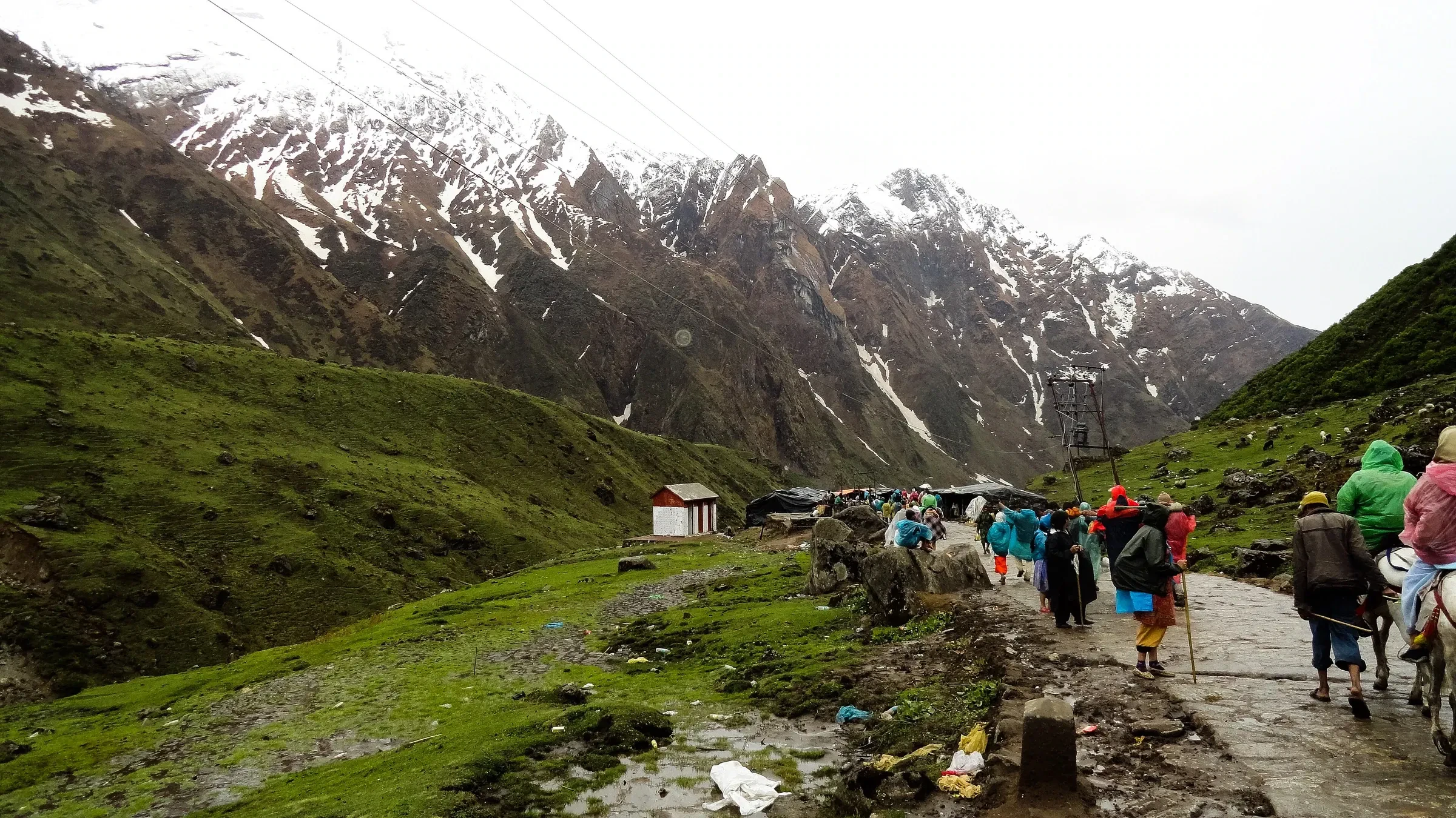 Pilgrims walking the mountain path towards Kedarnath beneath snow-dusted peaks