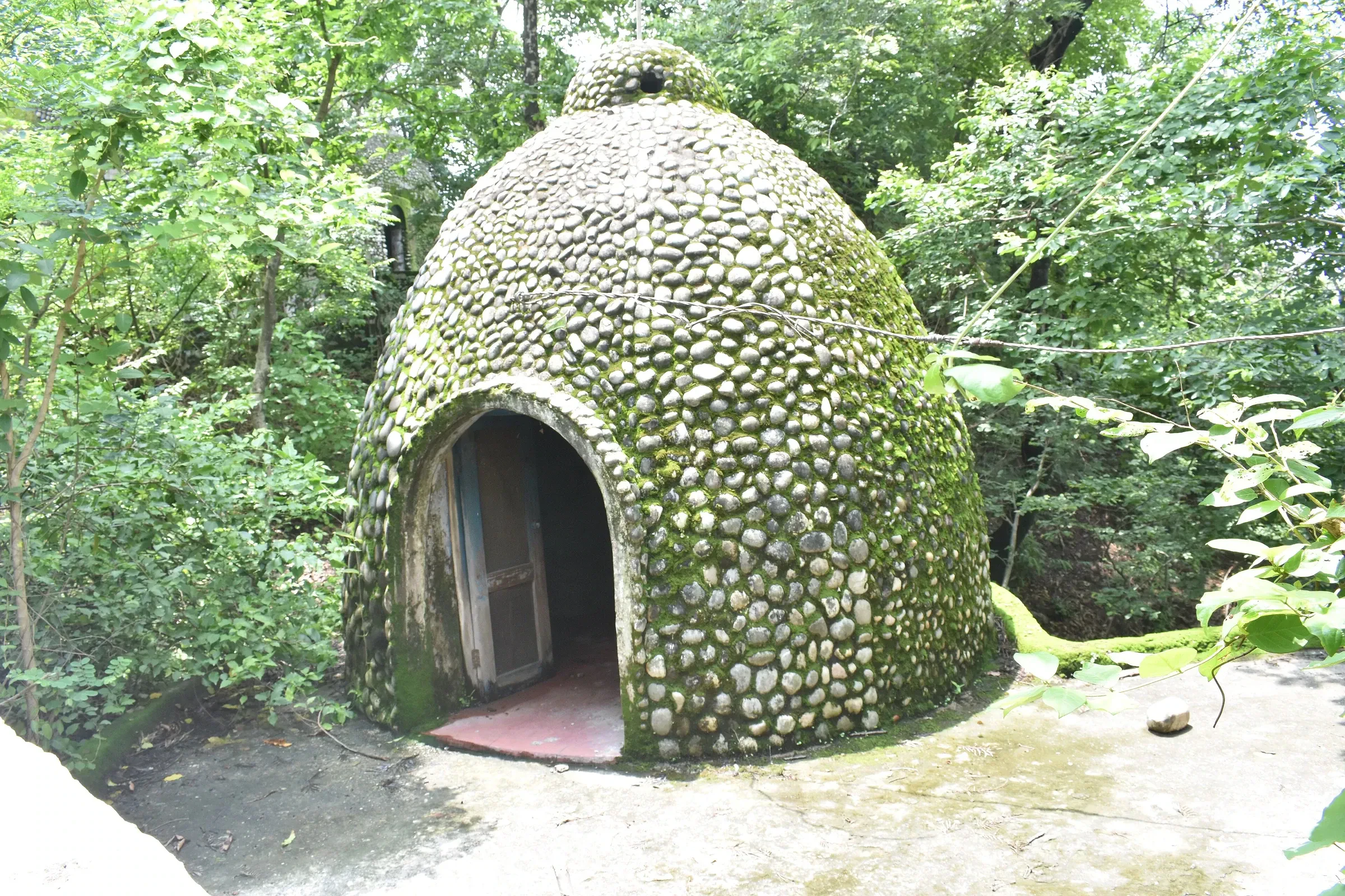 A stone-covered meditation hut among the trees at the abandoned Beatles Ashram in Rishikesh