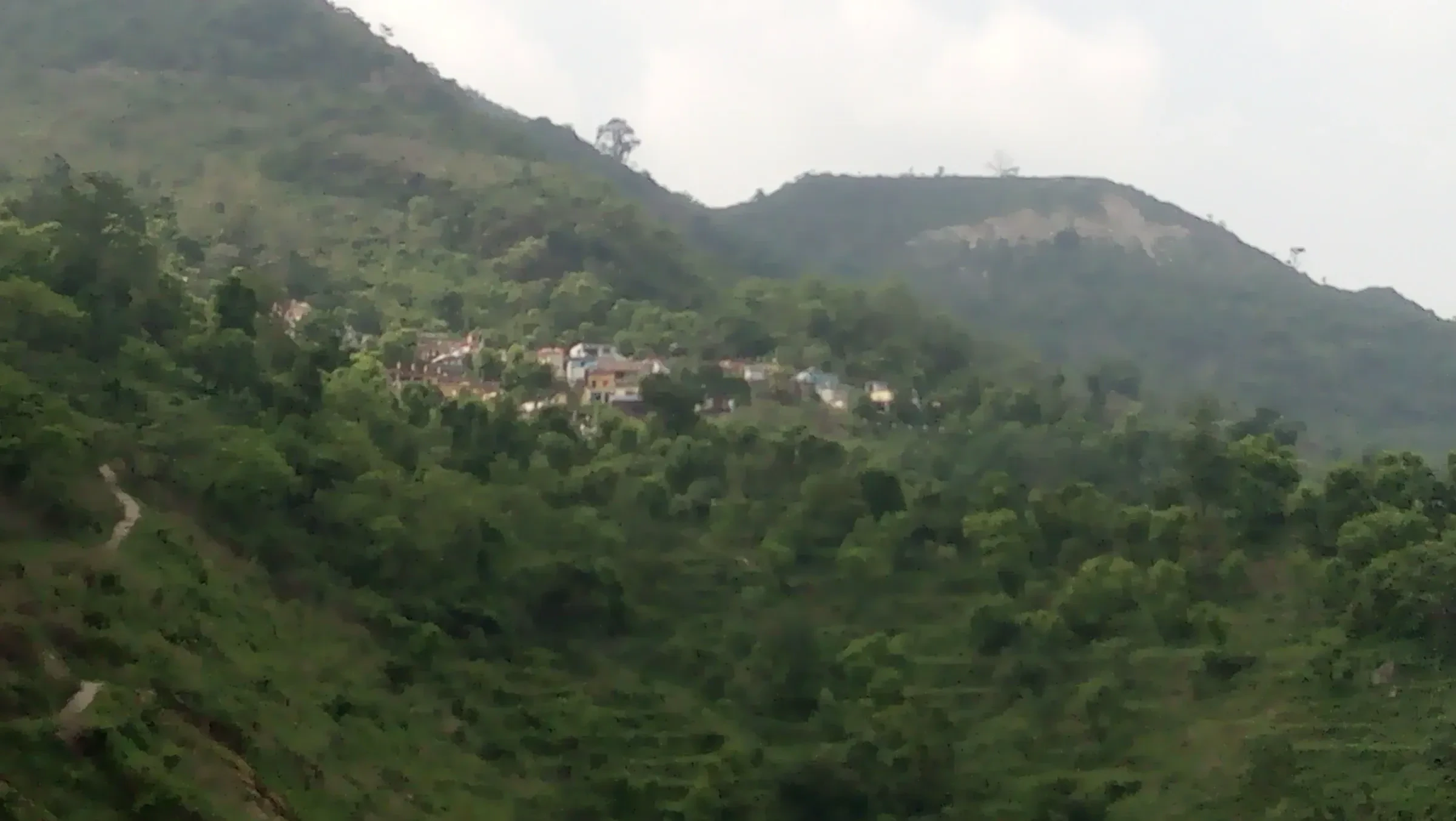 Forested hills and a small village in the Neelkanth area of Uttarakhand