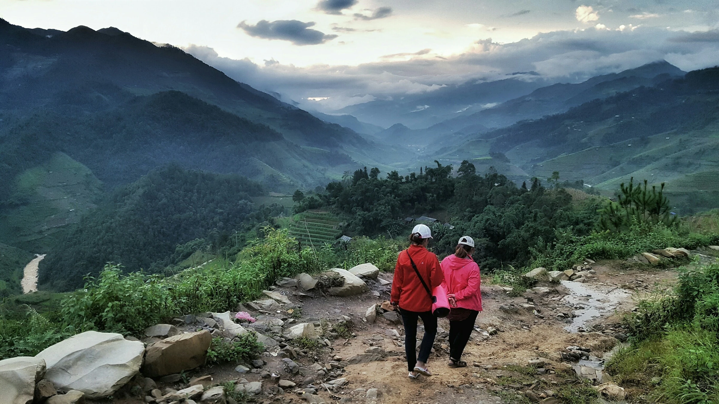 Two trekkers on a rocky trail above a misty mountain valley in northern Vietnam