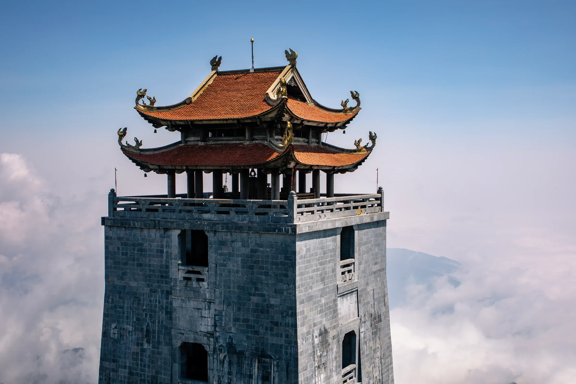 A tiled-roof temple tower rising above the clouds on Fansipan