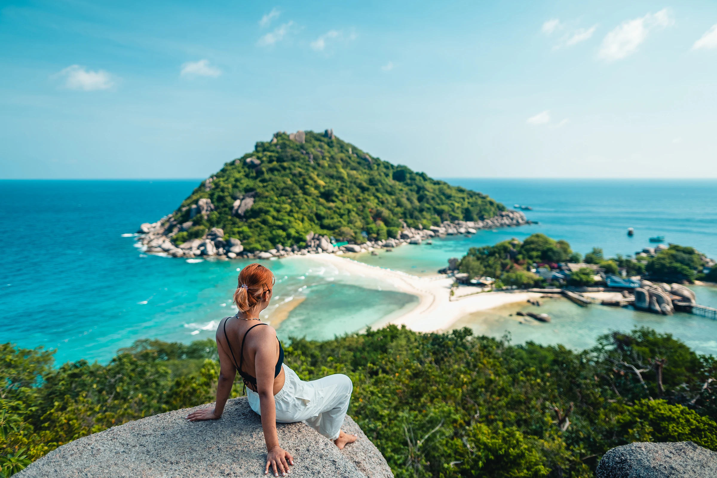 A woman sitting on a rock at the Koh Nang Yuan viewpoint, looking over the sandbar