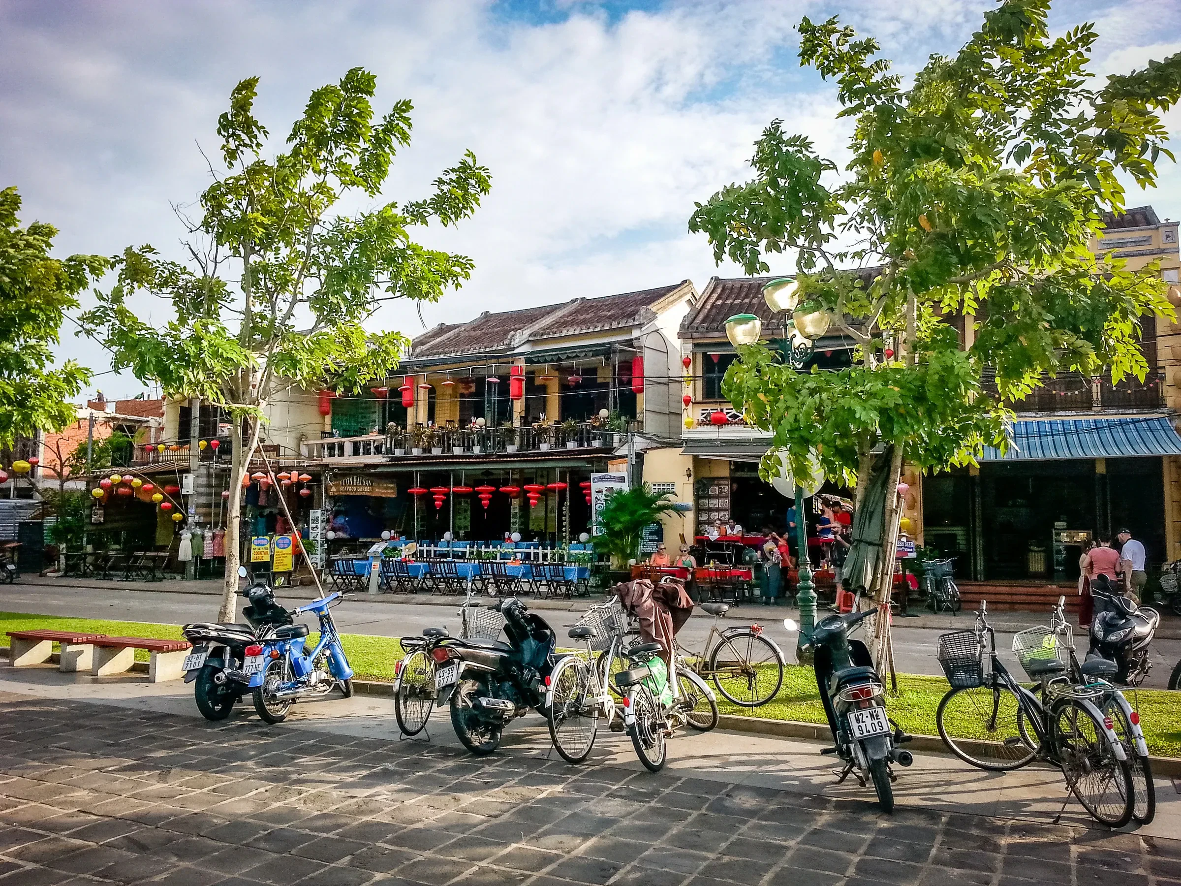 A tree-lined street of cafe fronts and parked bicycles in Hoi An's old town