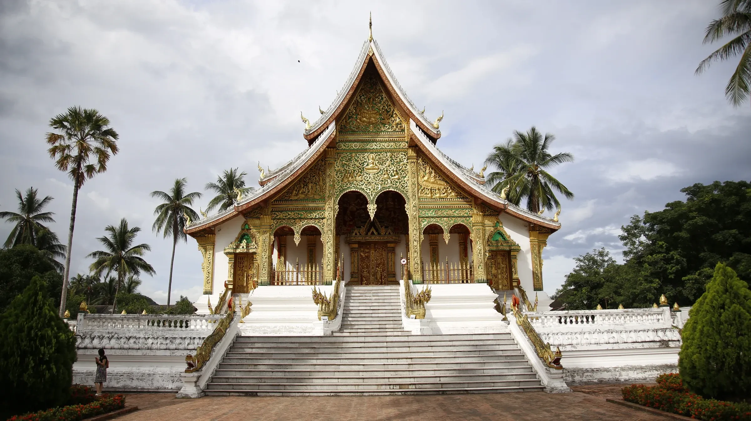 A gilded temple with a tiered roof and white steps in Luang Prabang