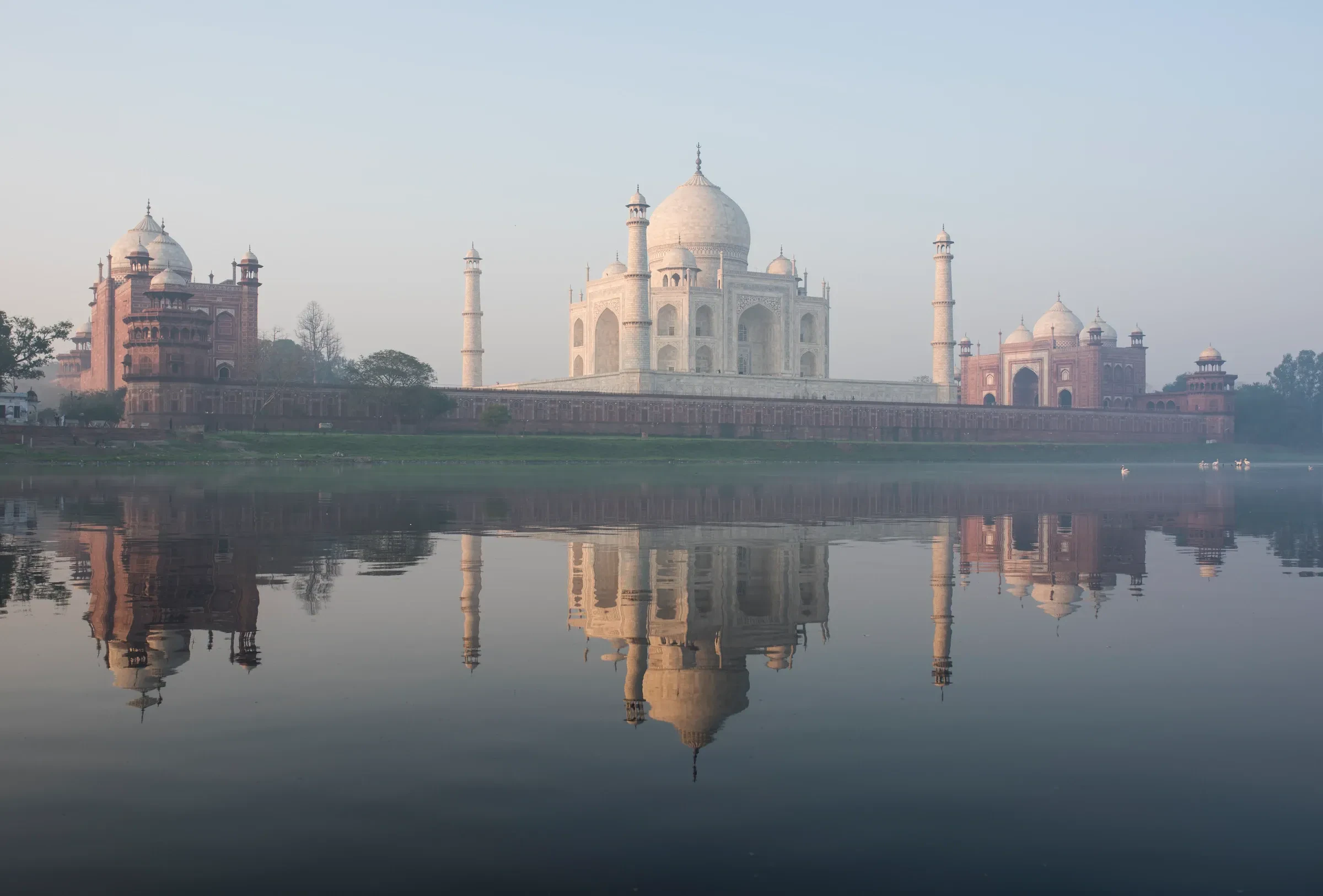 The Taj Mahal and its reflection in the river on a misty morning in Agra