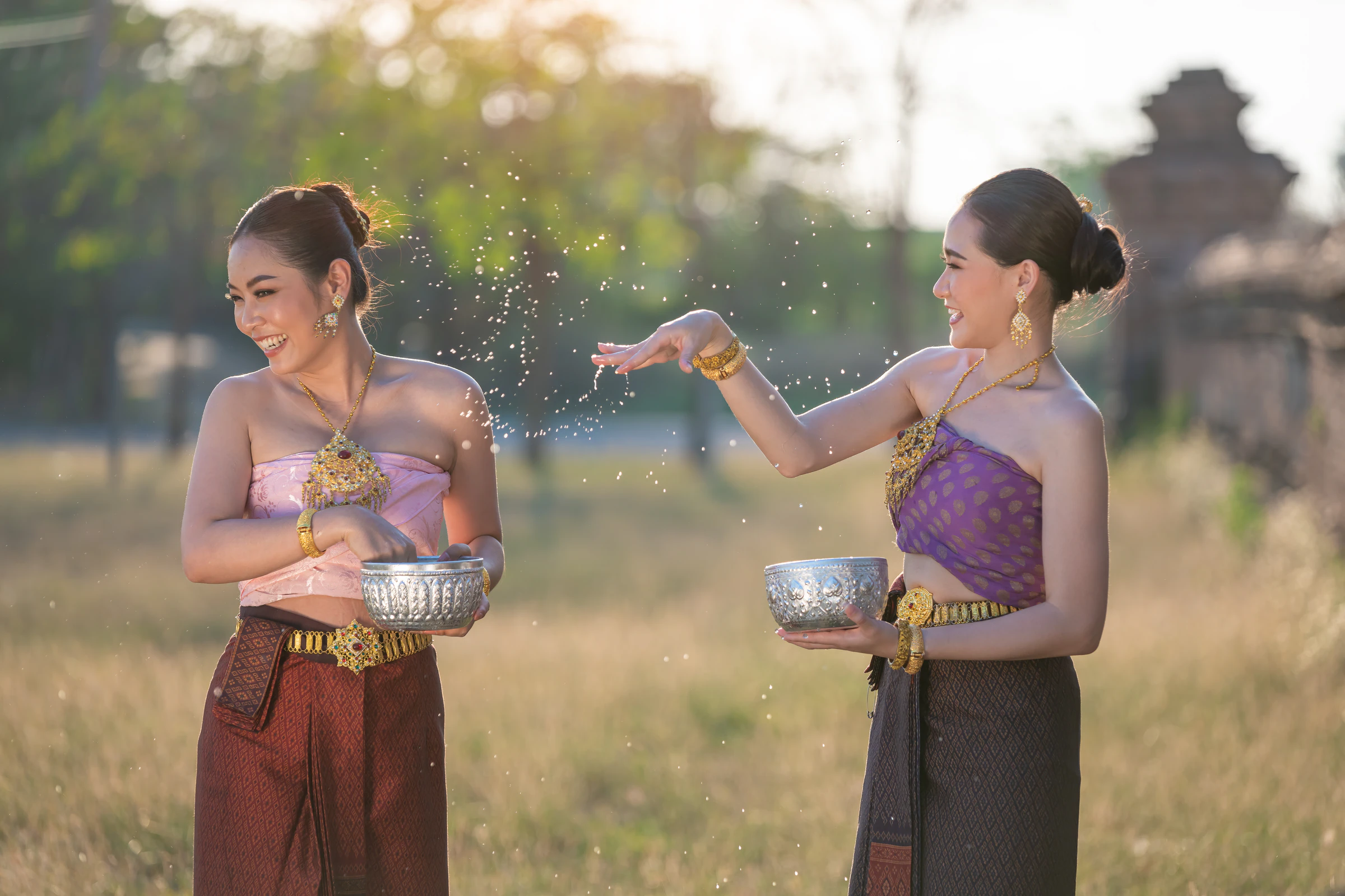 Two women in traditional dress celebrating Songkran outdoors