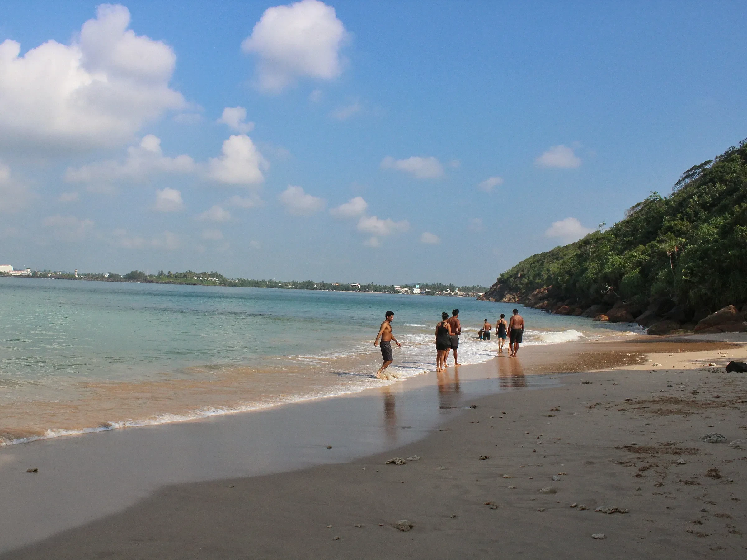 Swimmers on the sandy shore of Jungle Beach, Unawatuna, Sri Lanka