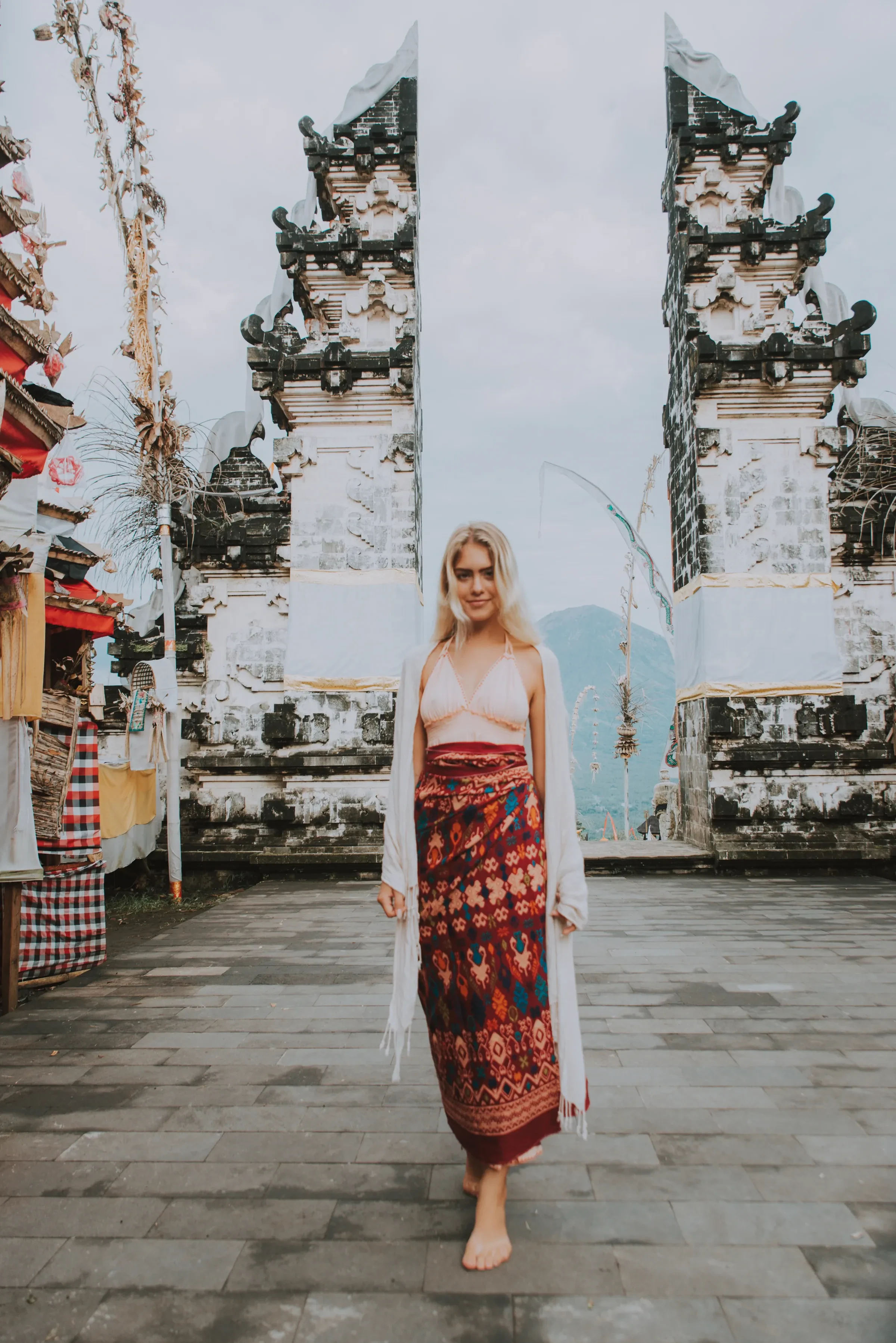 A woman in a red sarong at the split gate of Pura Lempuyang temple, Bali