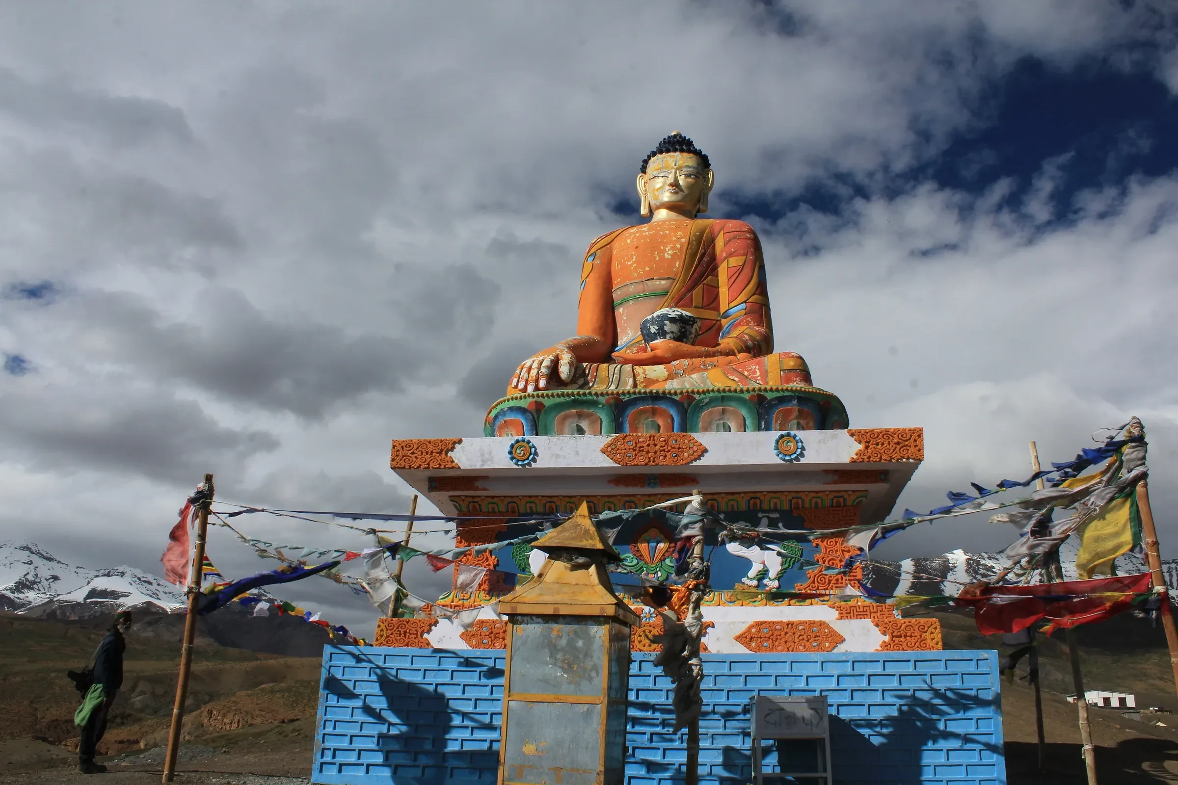 The giant Buddha statue at Langza village in Spiti, with prayer flags and cloud behind