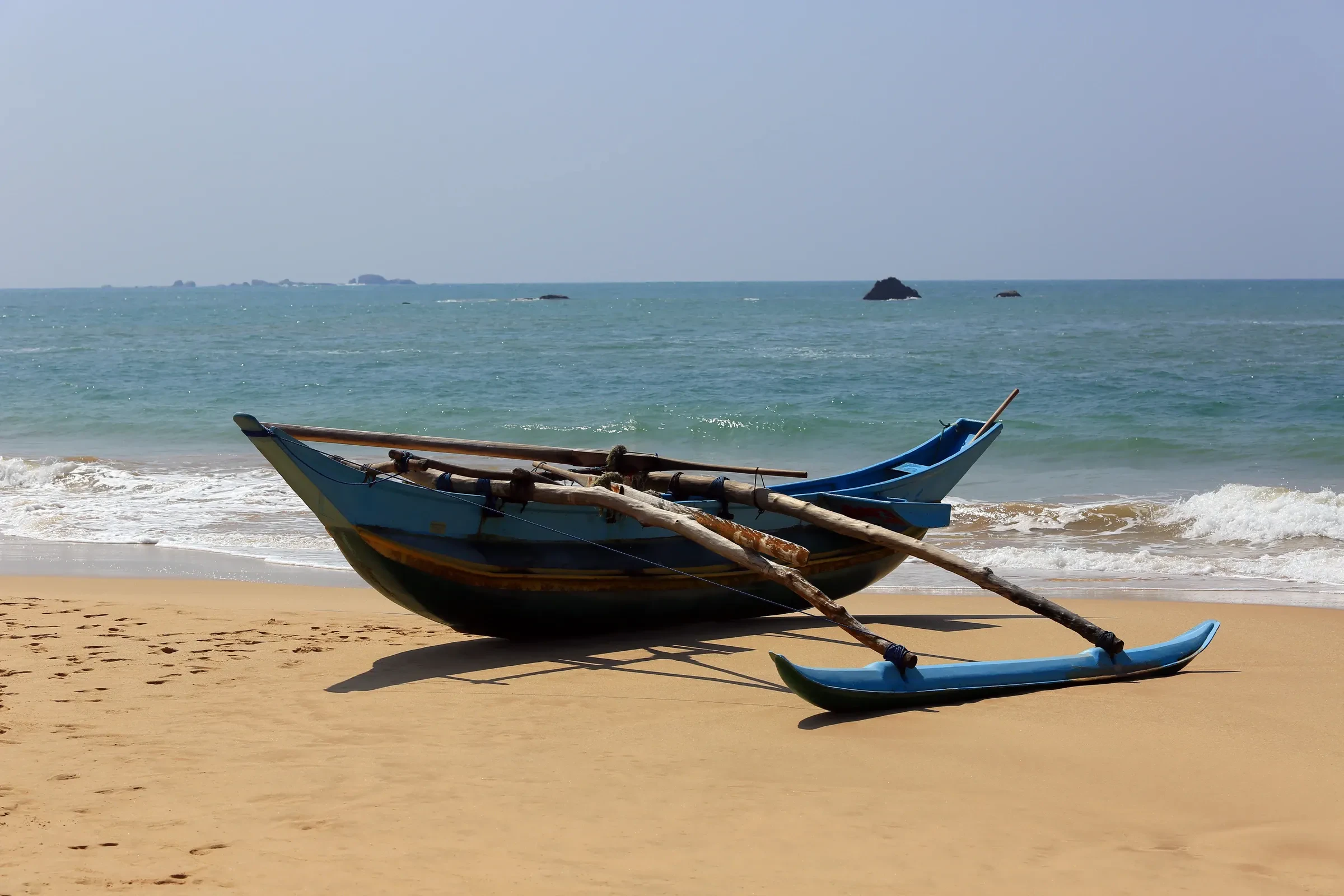 An outrigger fishing boat pulled up on a beach in Sri Lanka