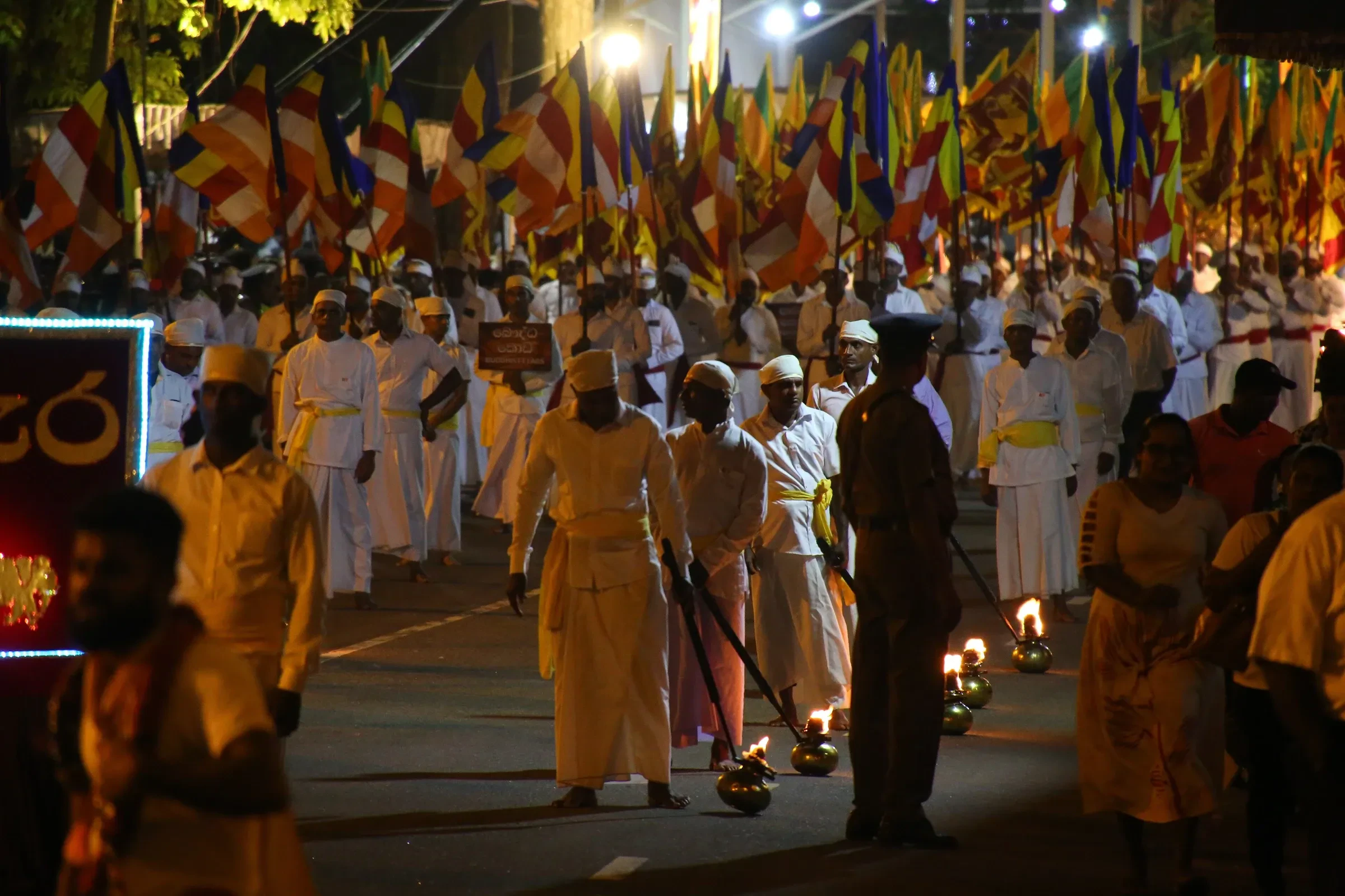 Marchers and Buddhist flags along a Colombo street at the start of the Navam Perahera