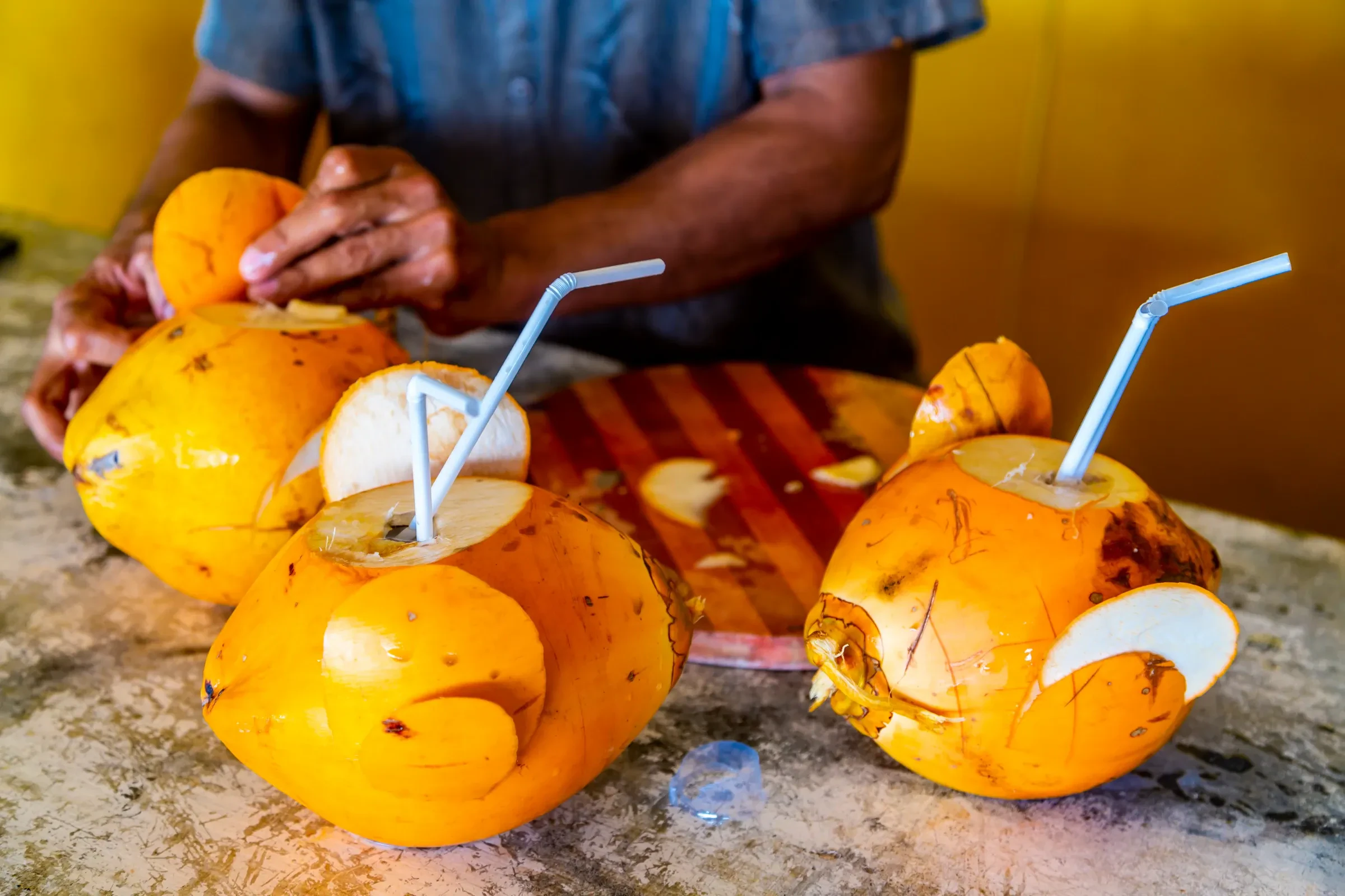 A vendor preparing king coconuts to drink at a market in Hikkaduwa