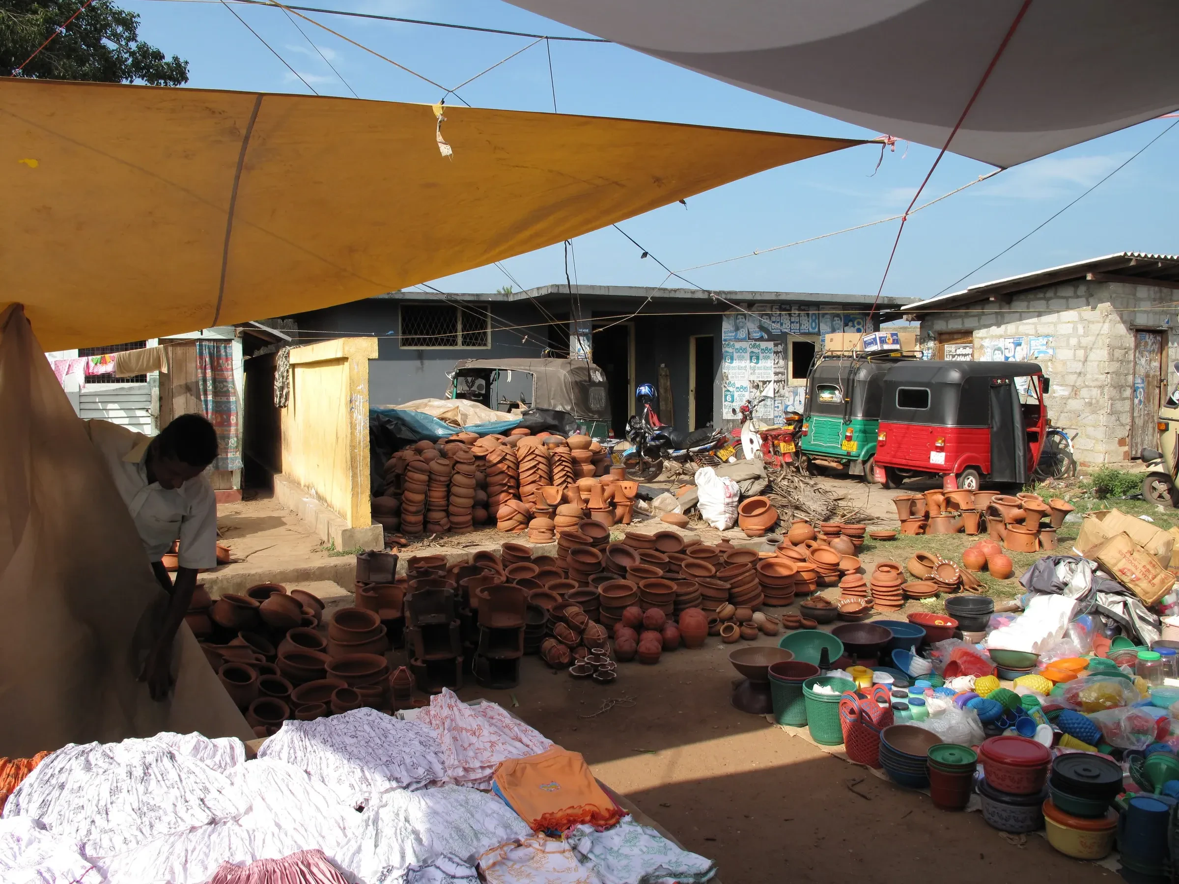 A market stall selling clay pots in Negombo, with a tuk-tuk behind