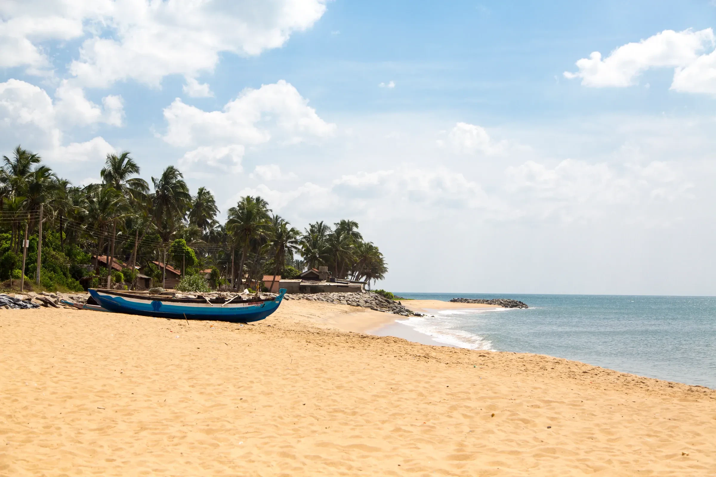 A blue fishing boat on the sand at Negombo beach