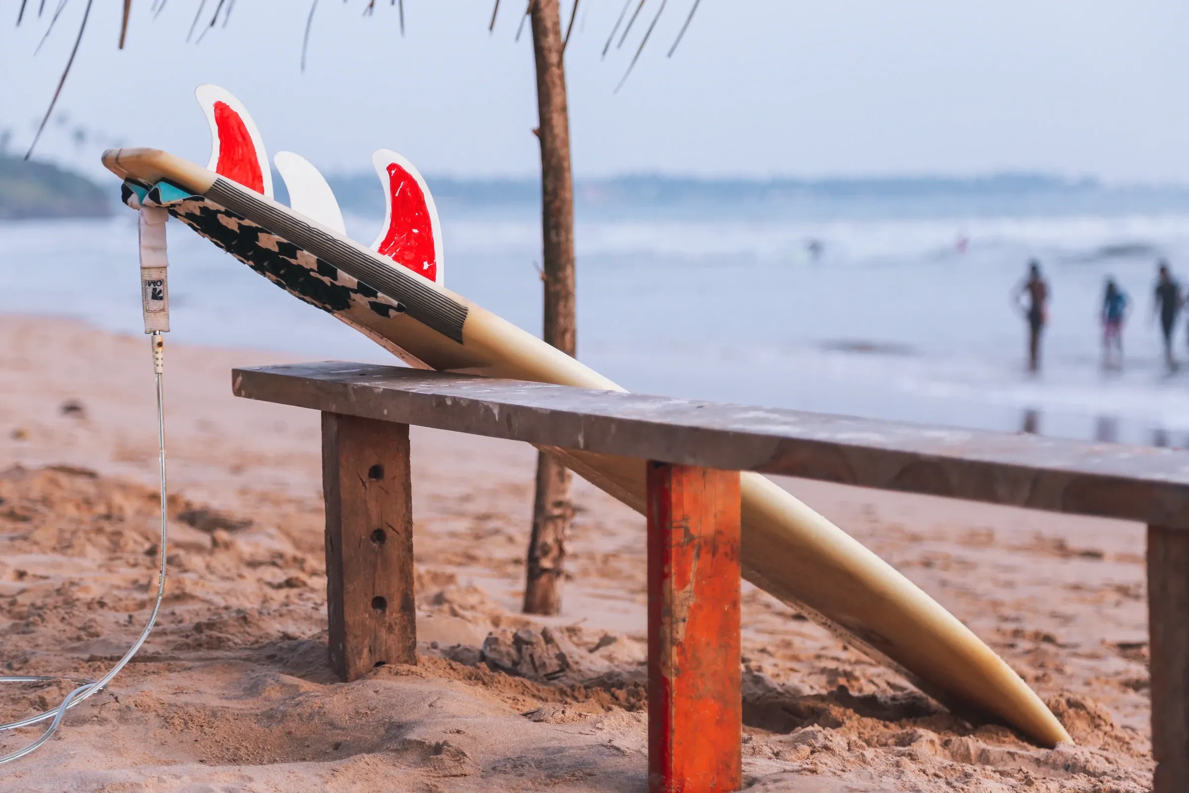 A surfboard resting on a wooden bench on a Sri Lankan beach