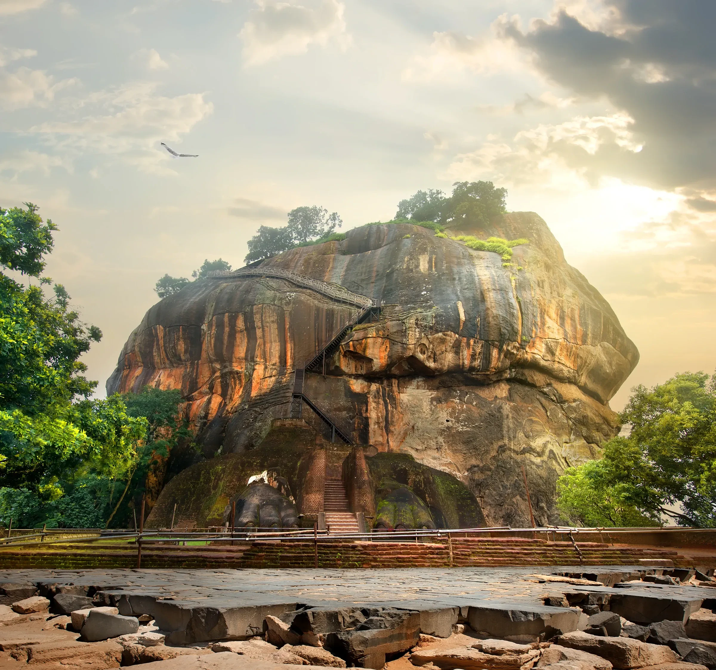 Sigiriya rock seen from its base, with light breaking through the clouds behind