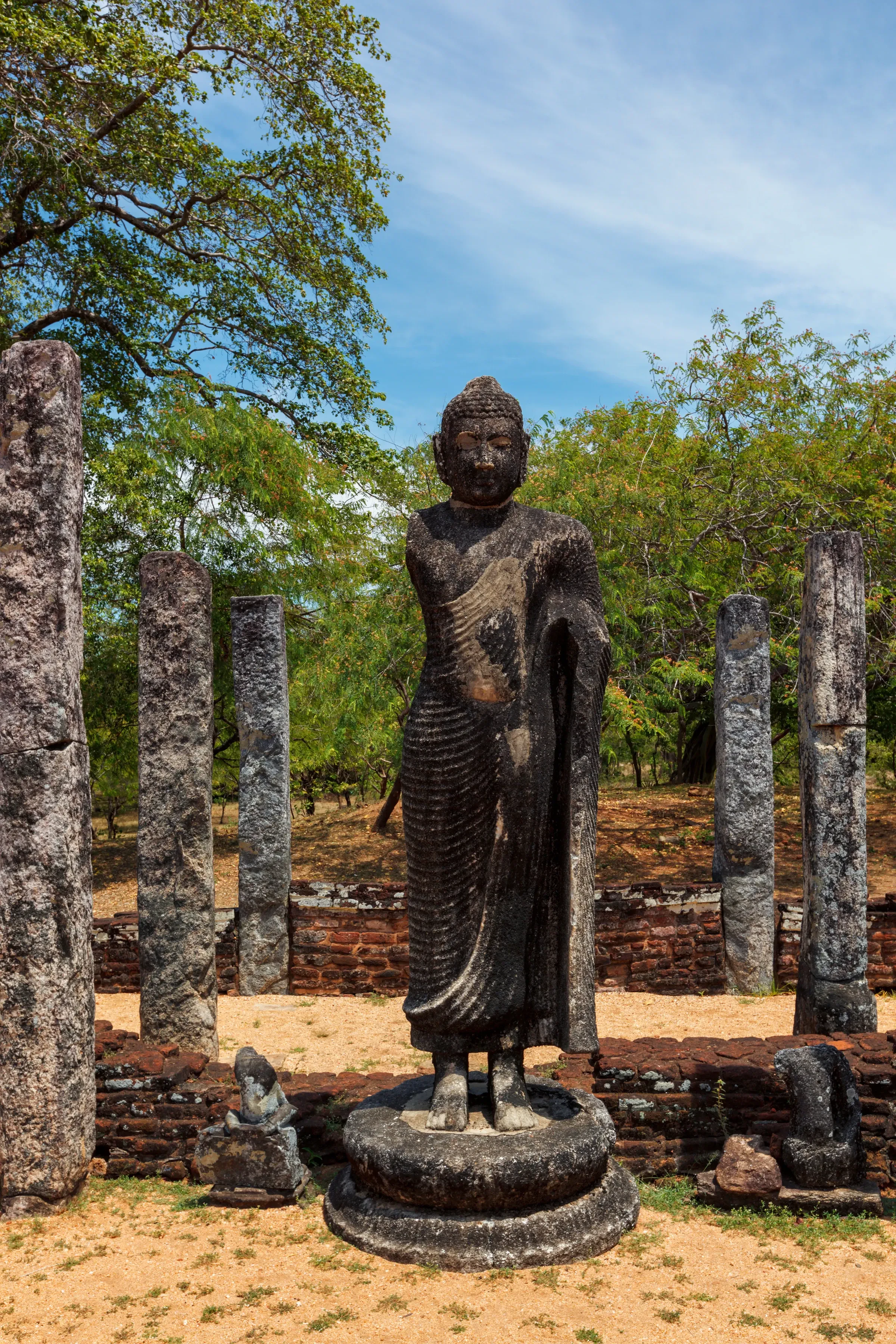 A standing Buddha statue among the ruined pillars at Polonnaruwa