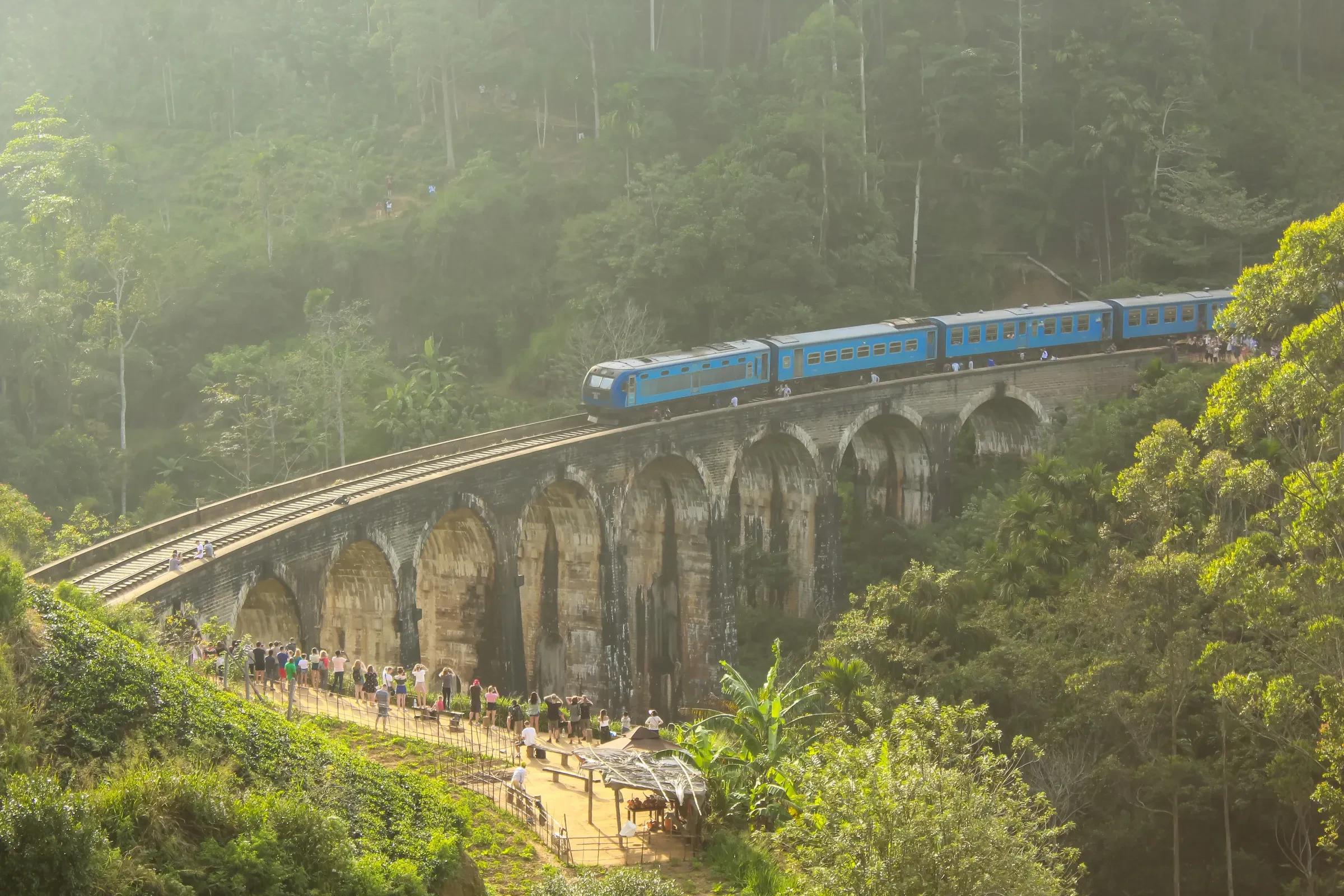 A blue train crossing the Nine Arches Bridge near Ella