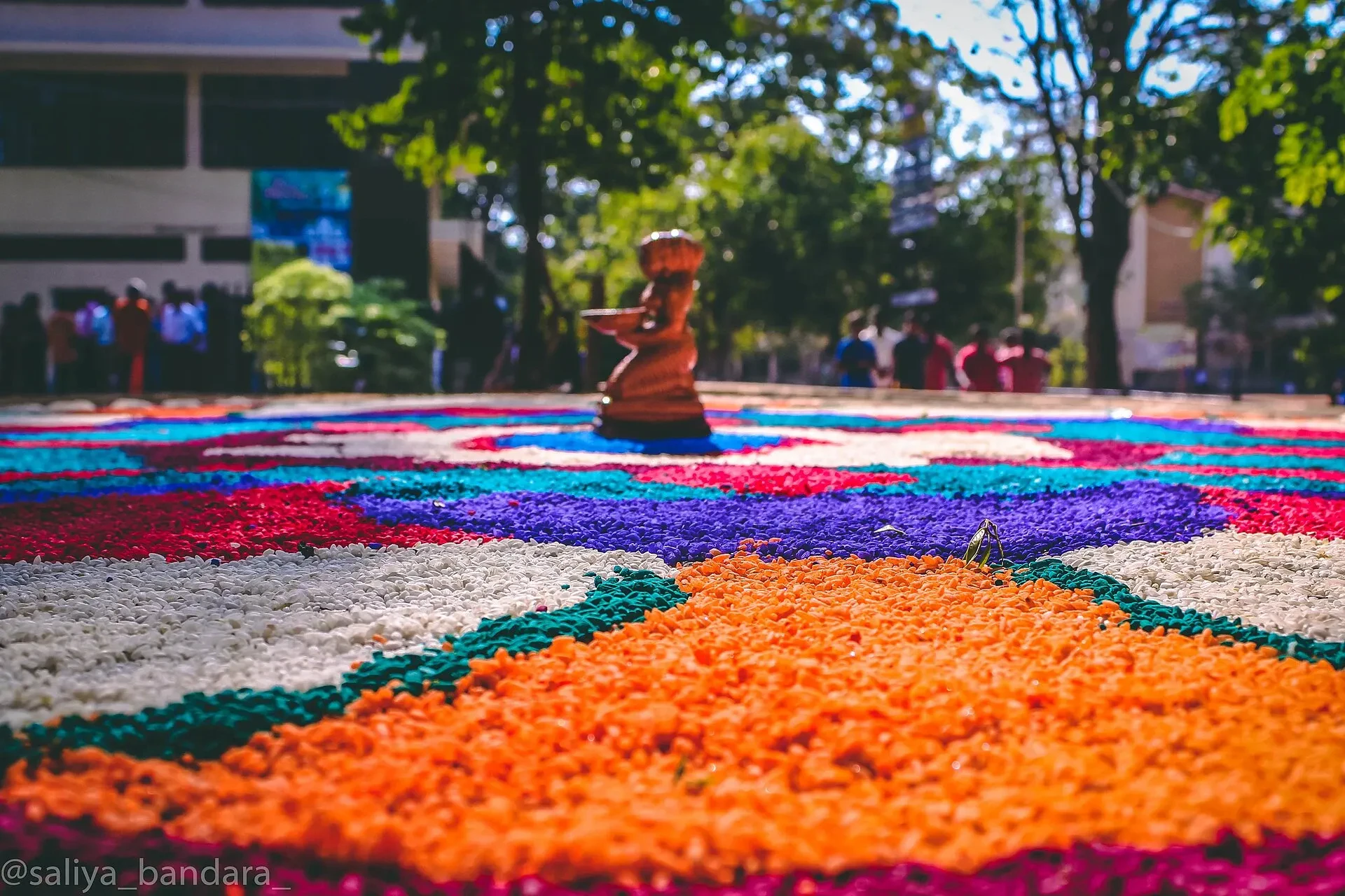 A rice and flower floor pattern with a brass oil lamp at a Sri Lankan New Year display