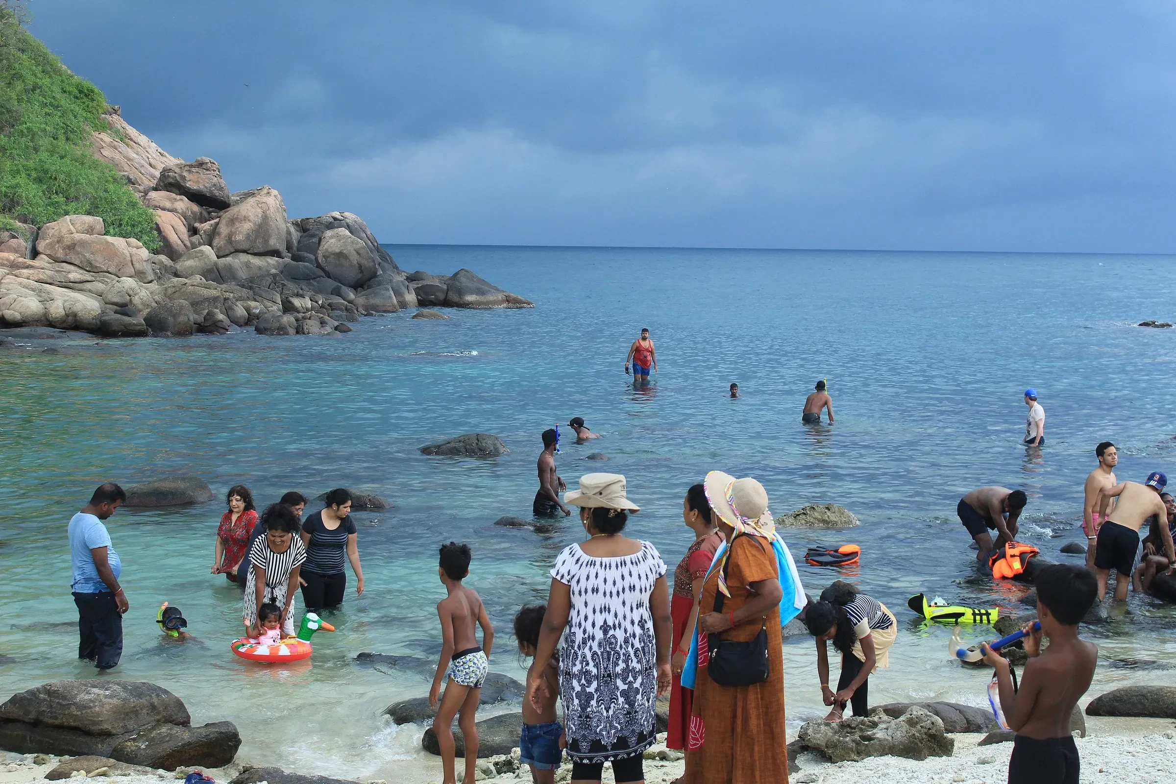 Visitors paddling in the shallows among the rocks at Pigeon Island National Park