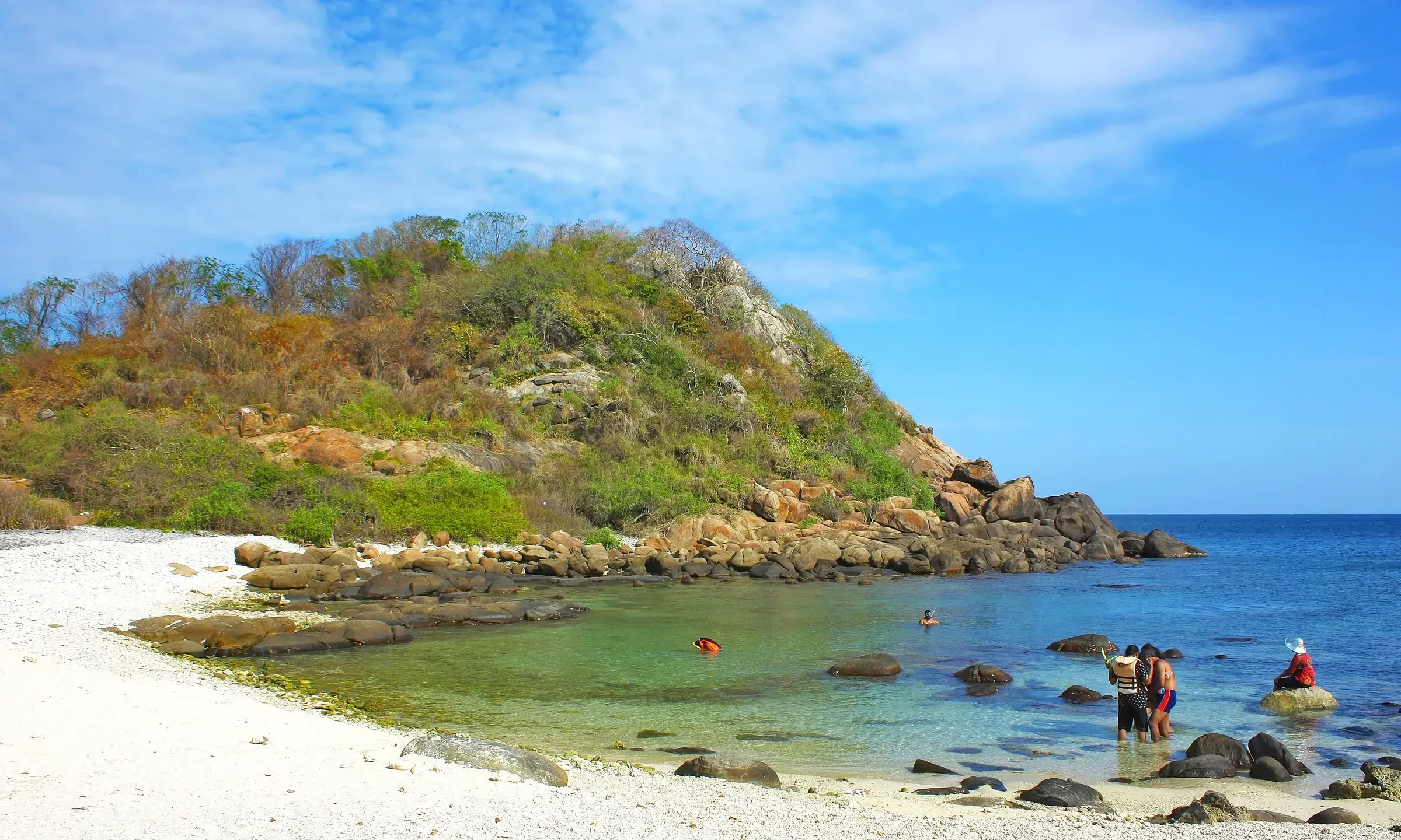 Visitors wading in the clear shallows beside Pigeon Island National Park near Trincomalee, Sri Lanka