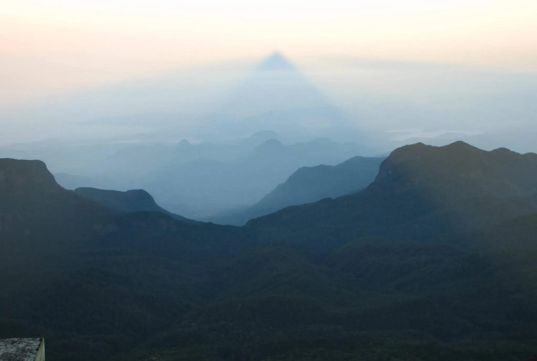 The triangular shadow of Adam's Peak stretching across the hills at dawn