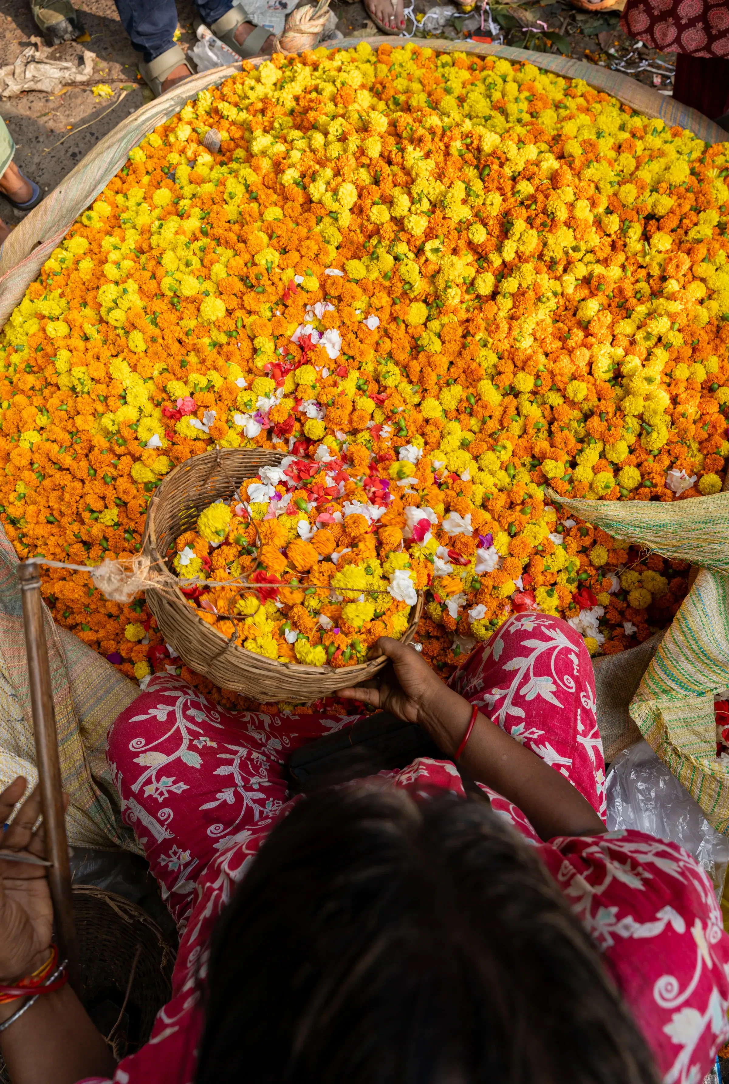 A woman sorting marigolds and other flowers in baskets at a flower market in India
