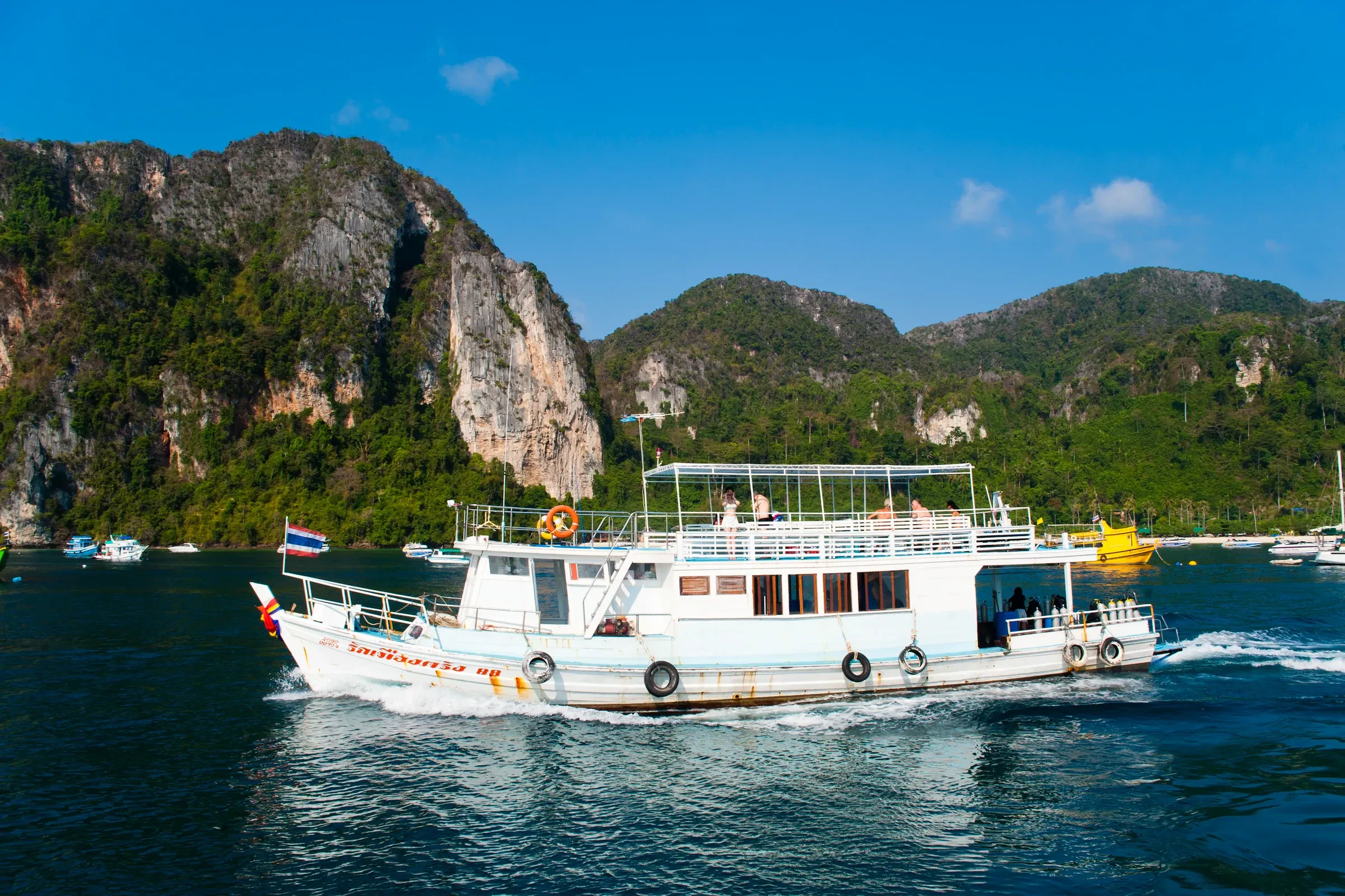 A passenger ferry passing green limestone cliffs off Koh Phi Phi