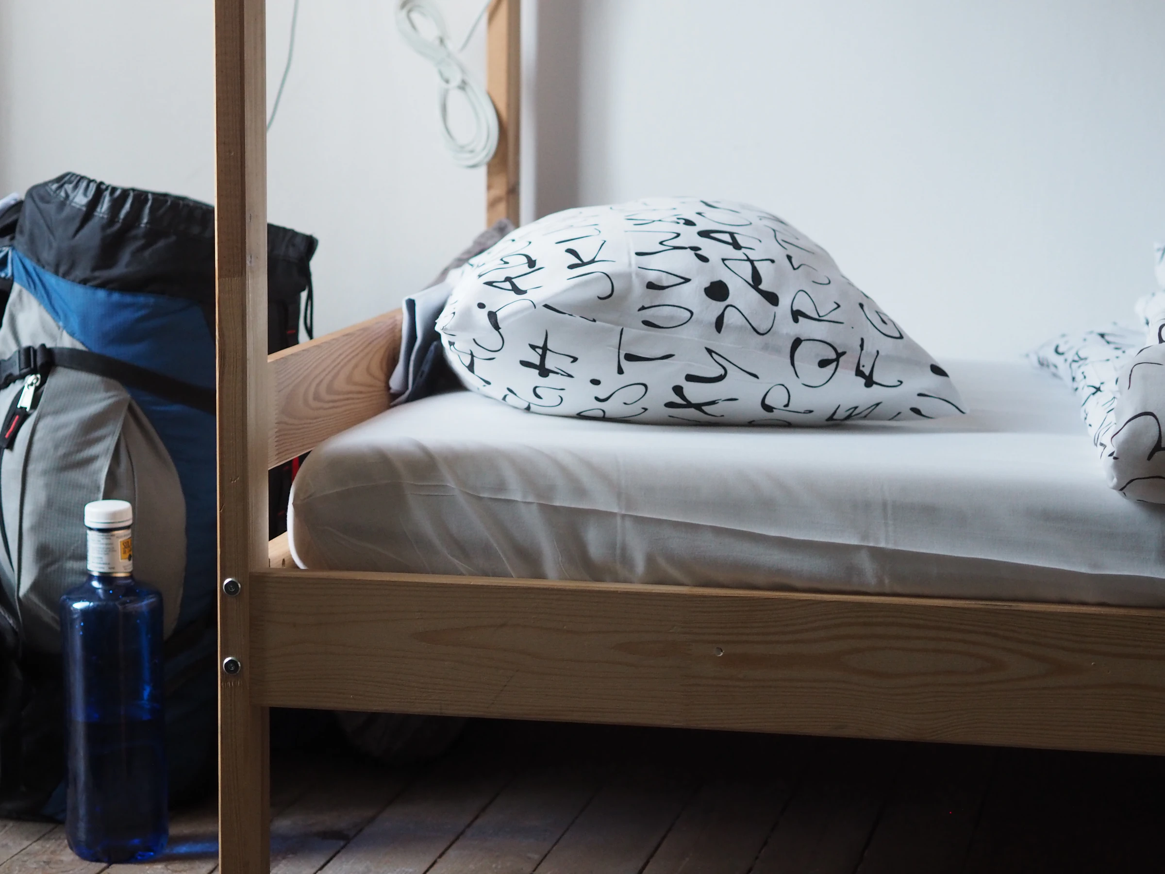 A backpack and a water bottle beside a wooden bed