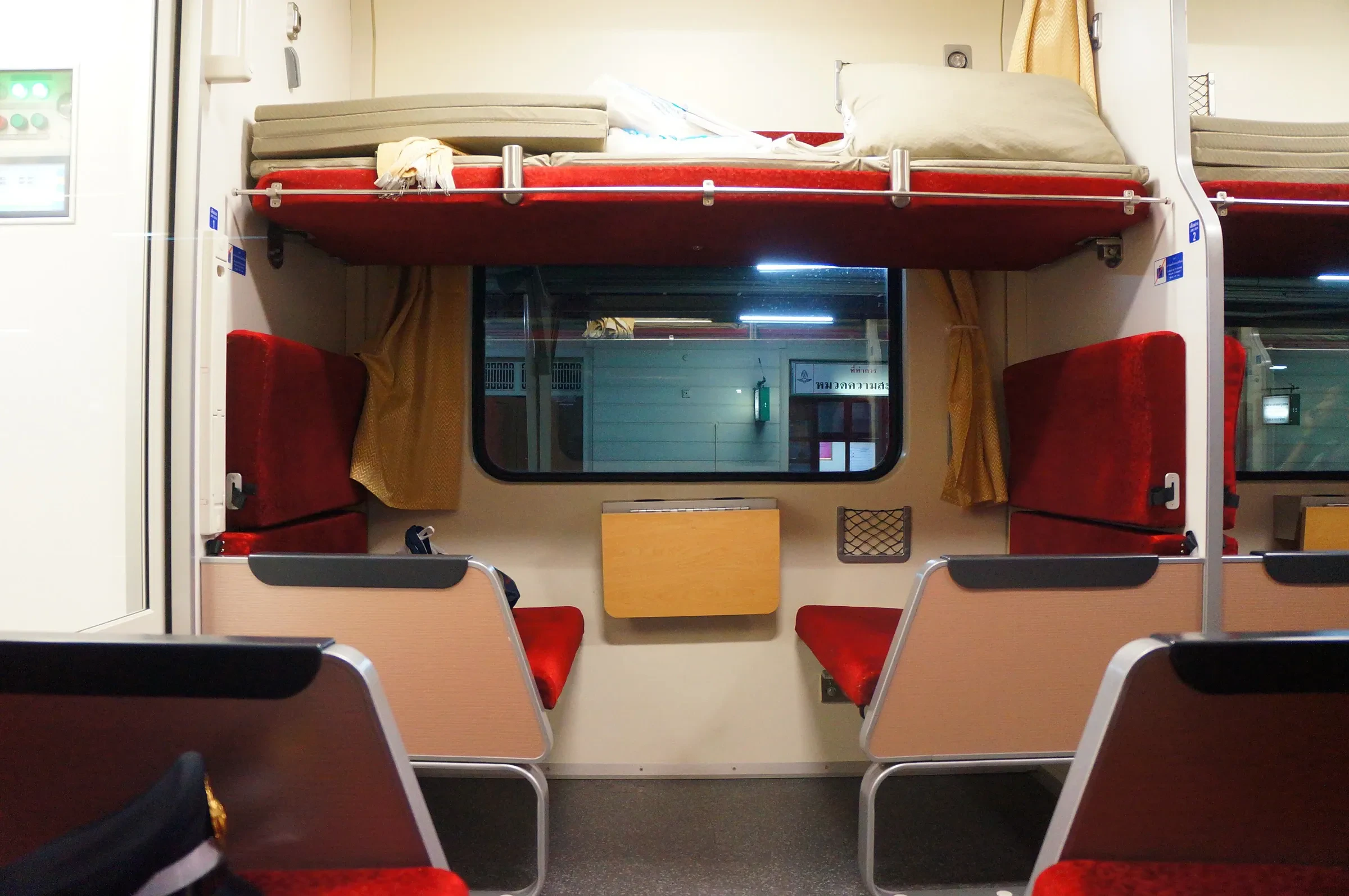 A second-class sleeper compartment on a Thai State Railway train, with the upper berth made up above facing seats