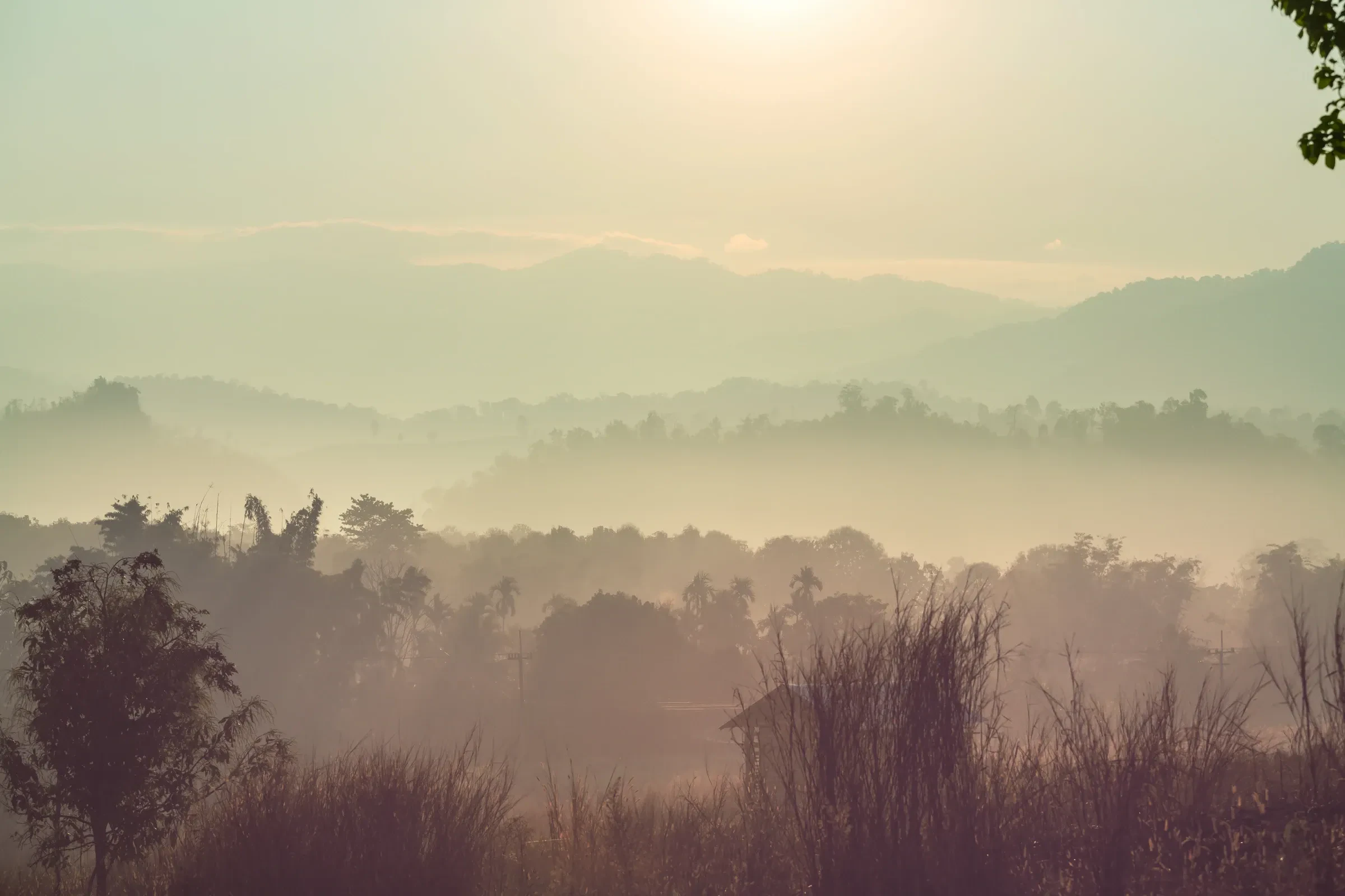 Hazy light over layered forested hills in northern Thailand