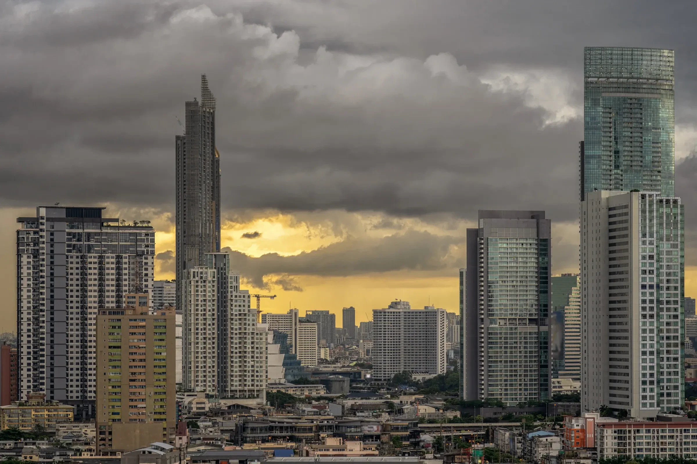 Dark storm clouds over the skyscrapers of Bangkok at sunset