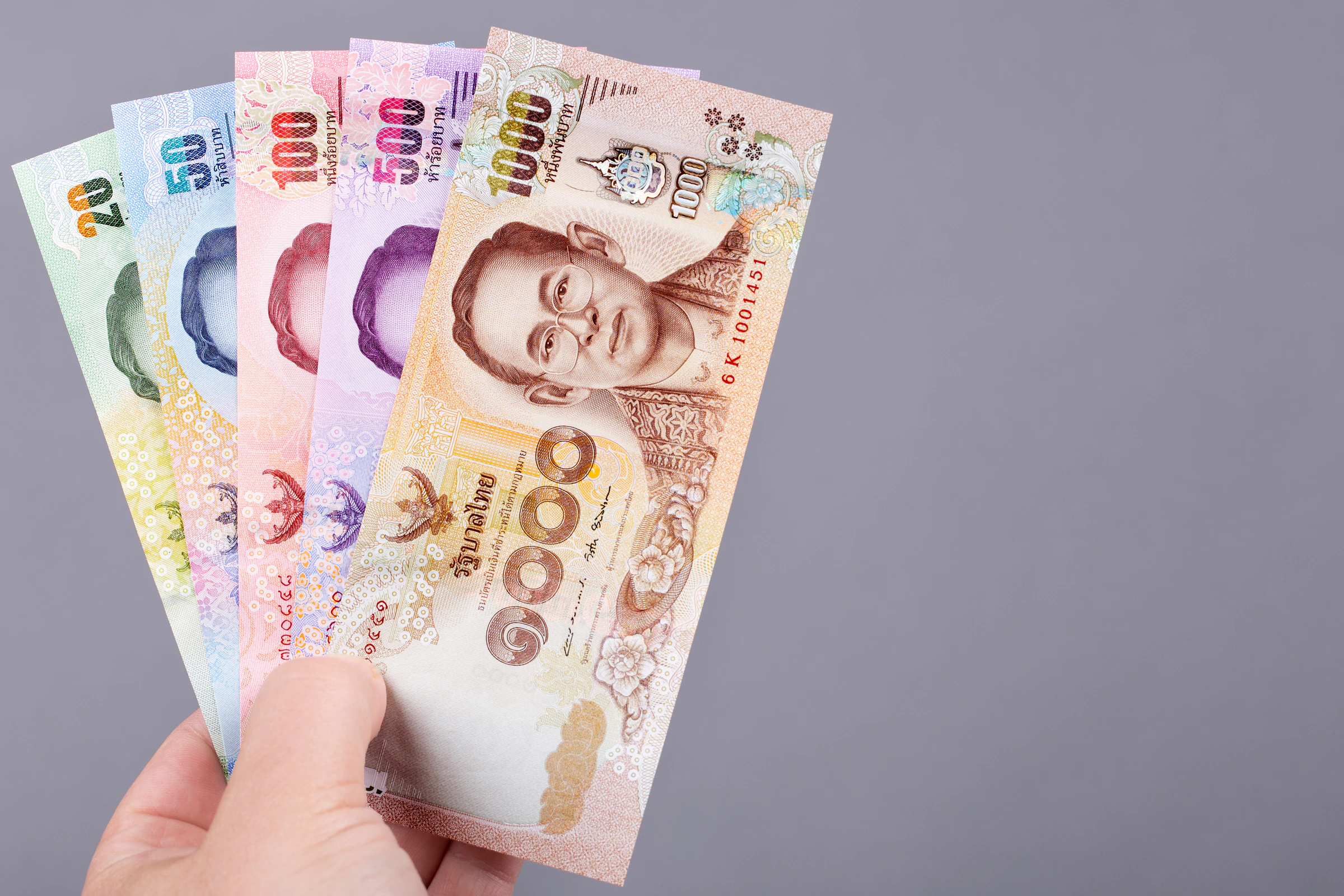Thai baht banknotes held in someone's hand