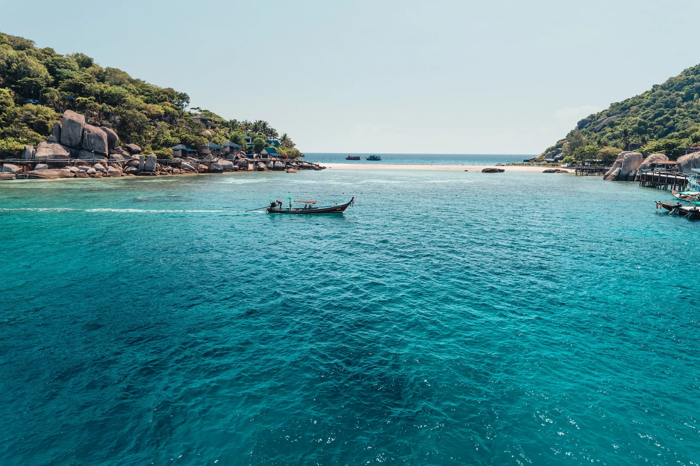 A longtail boat moored off Koh Tao's clear water, with the island's hills behind